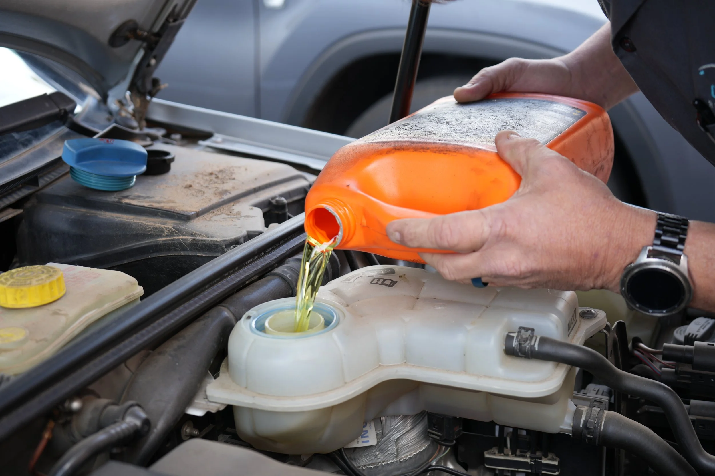 Close-up of a mobile mechanic performing an oil change on a vehicle.
