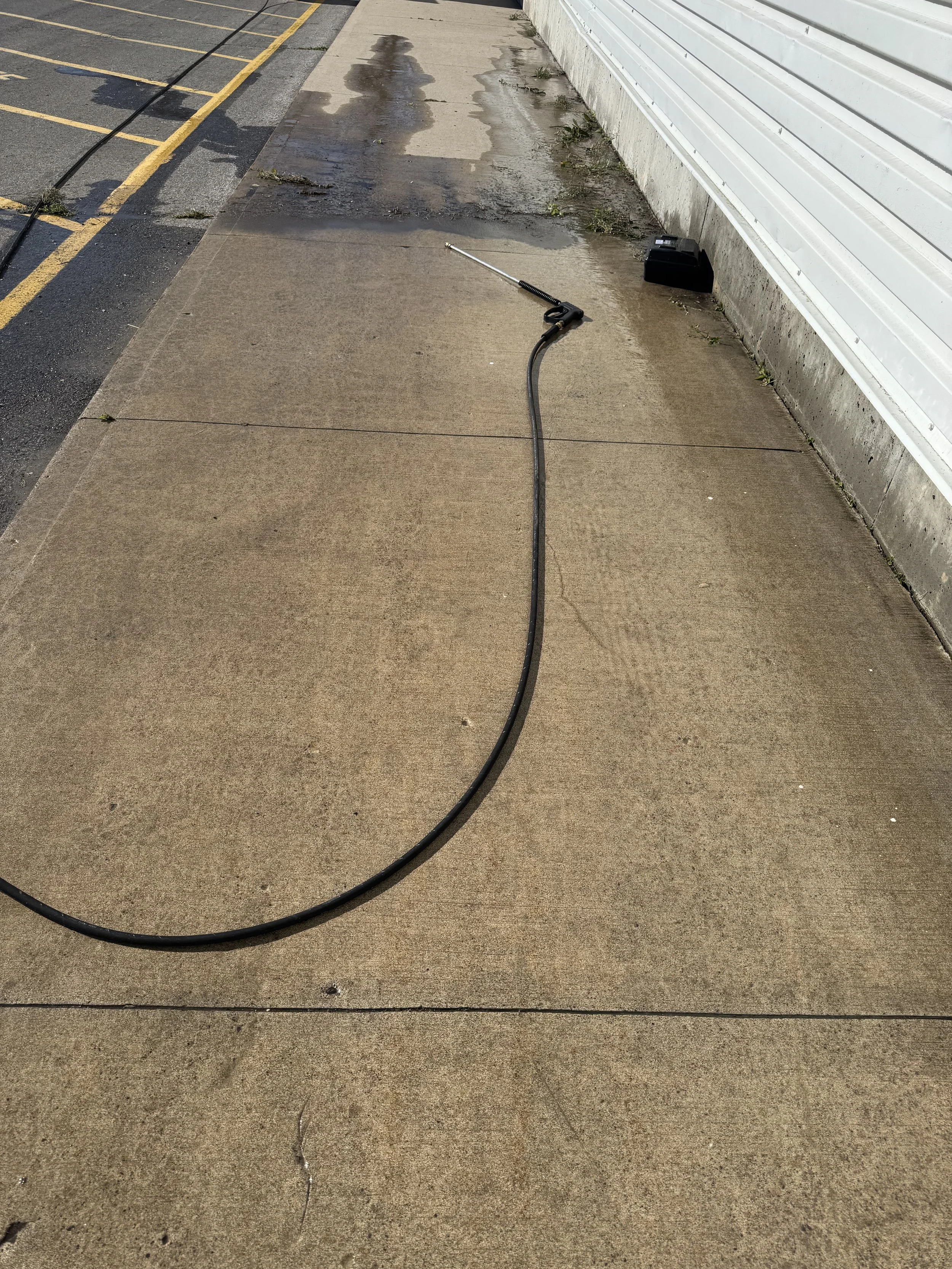 Dirt and grime removed from a sidewalk by pressure washing.