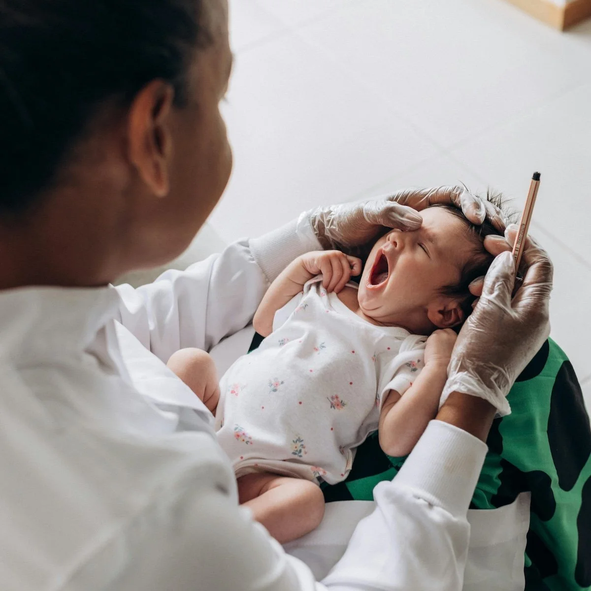 A doctor examining a young child's throat with a tongue depressor while the child yawns.