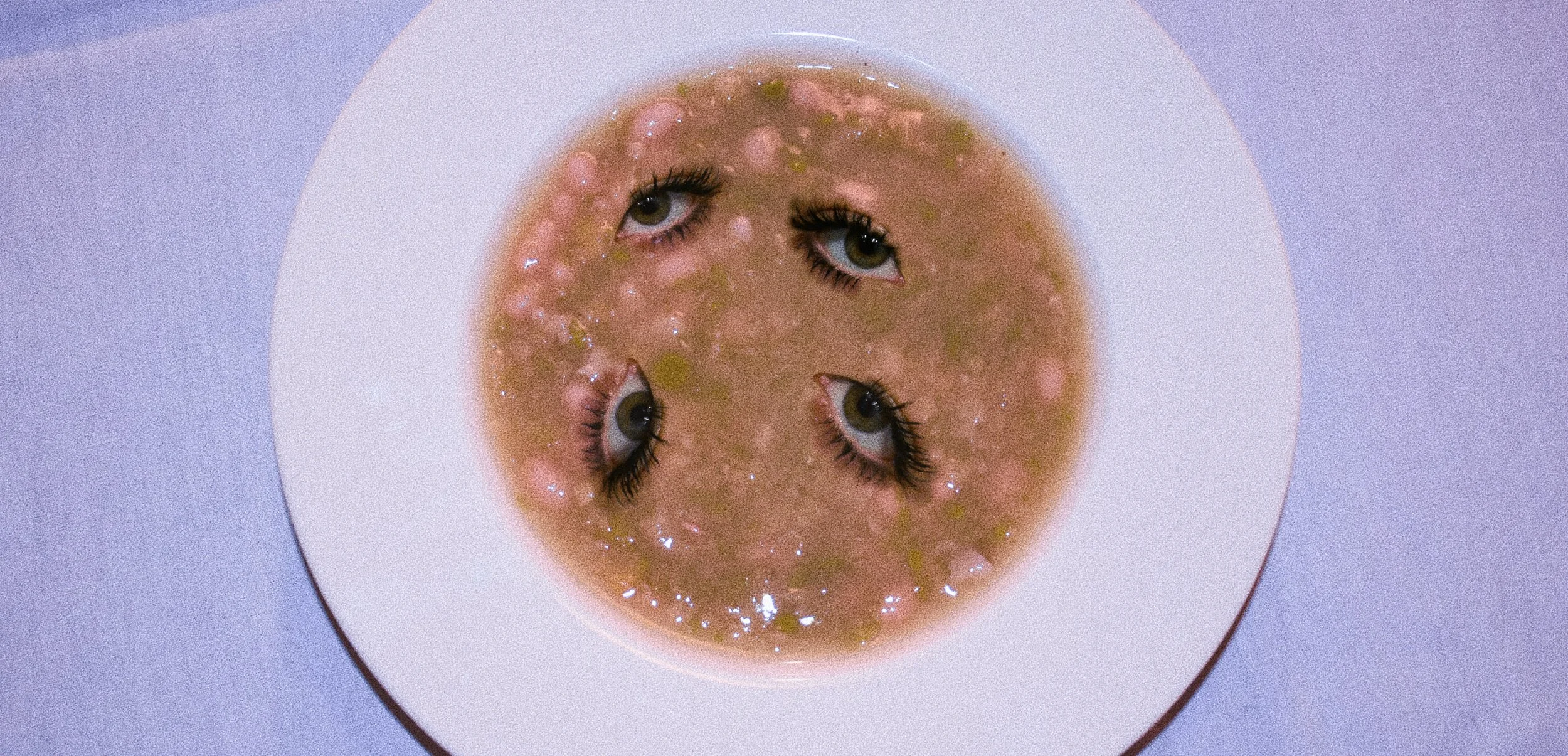 Una ciotola di zuppa con quattro teste umane con occhi, naso e bocca interi, sovrapposte e semi-immersi nella zuppa.