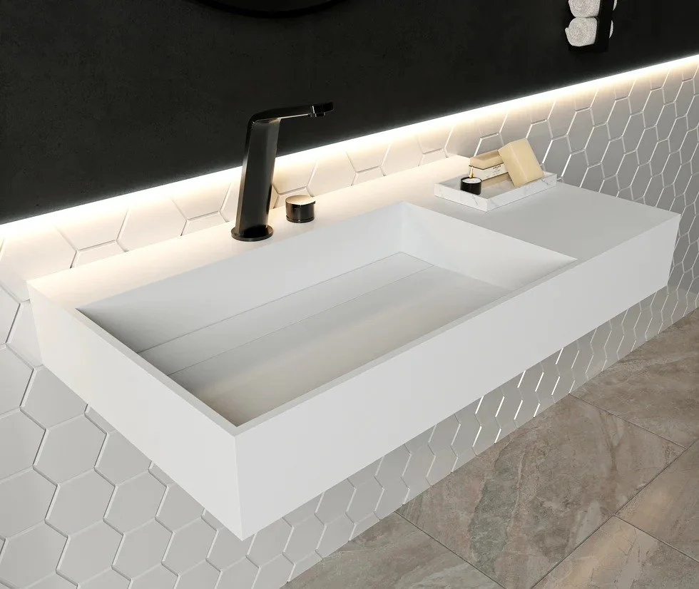 Modern white bathroom sink with black faucet, set against a wall with white hexagonal tiles and a black backdrop, illuminated with LED lighting.