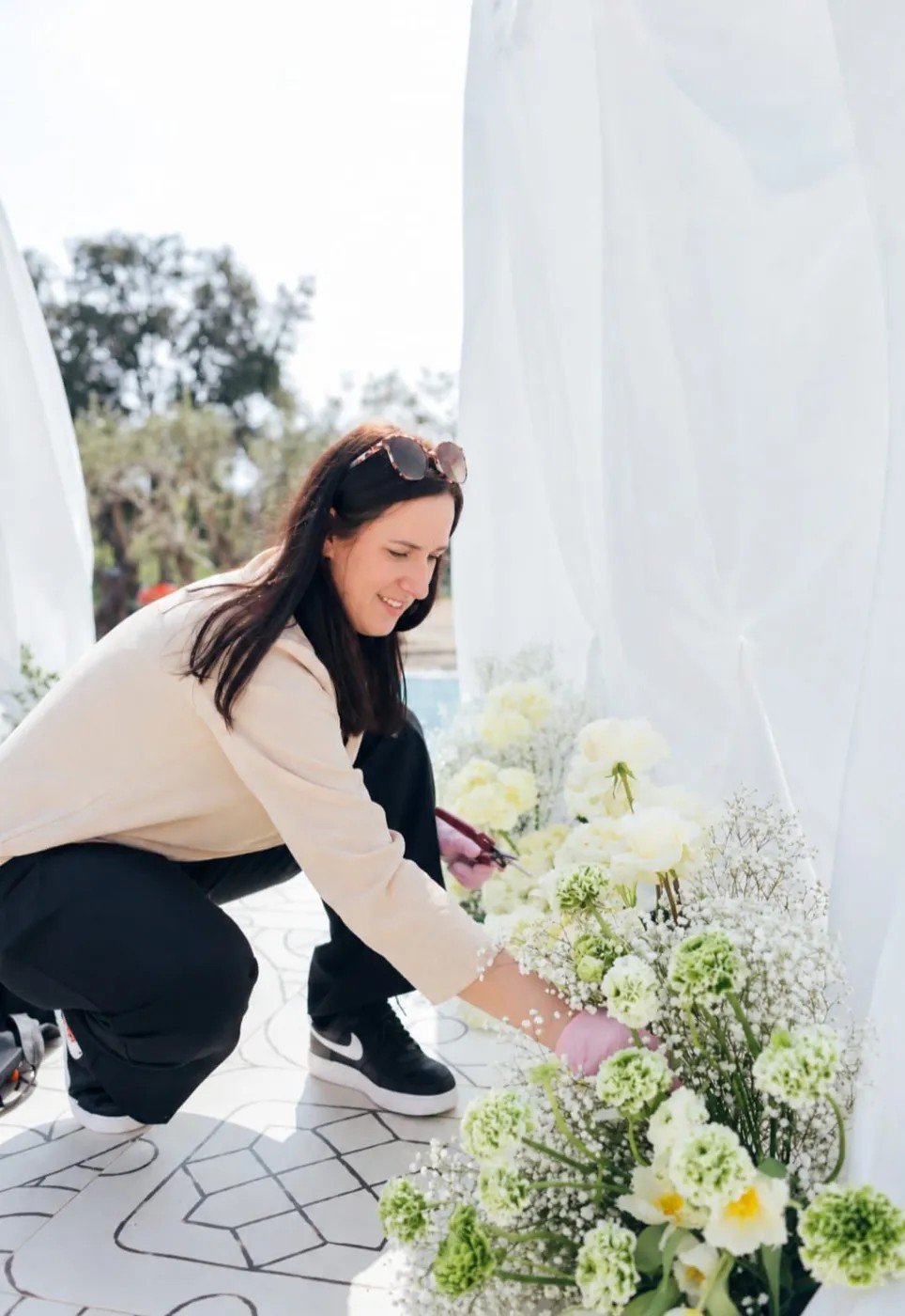 Julie, fleuriste de la Maison, composant un arrangement de fleurs blanches et vertes.