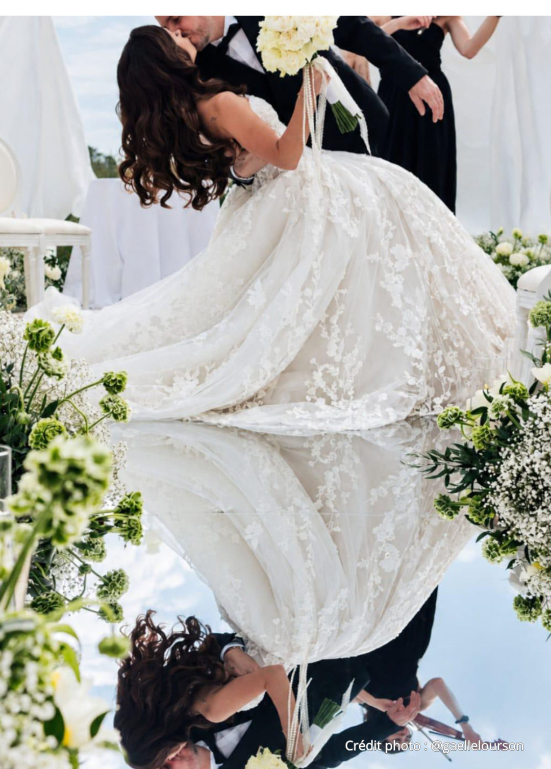 Un couple lors d'une cérémonie de mariage avec la mariée en robe blanche et le marié en costume noir, échangeant un baiser.