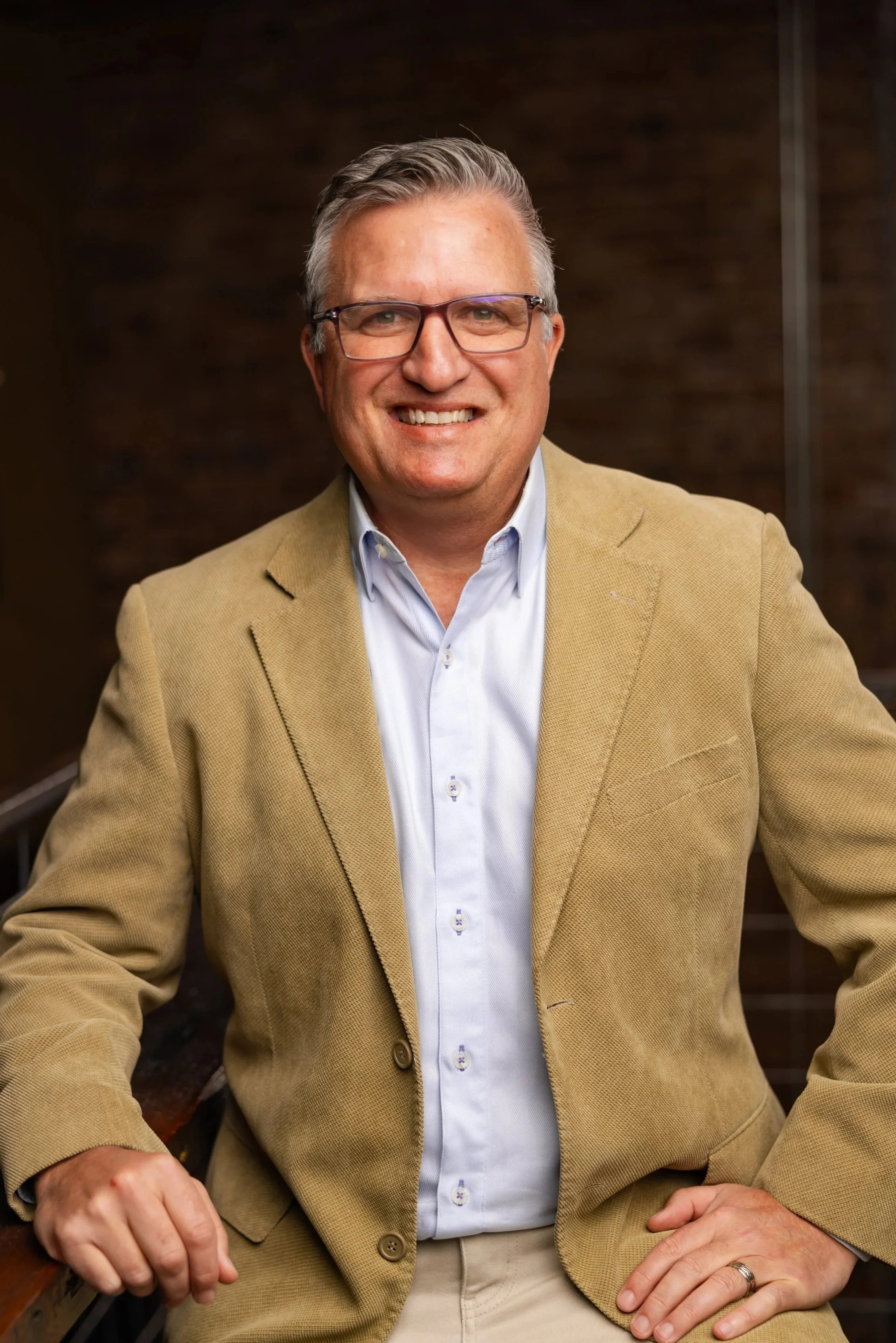 Mark McCary, founder of EagleWorks AI, in glasses and a beige blazer.