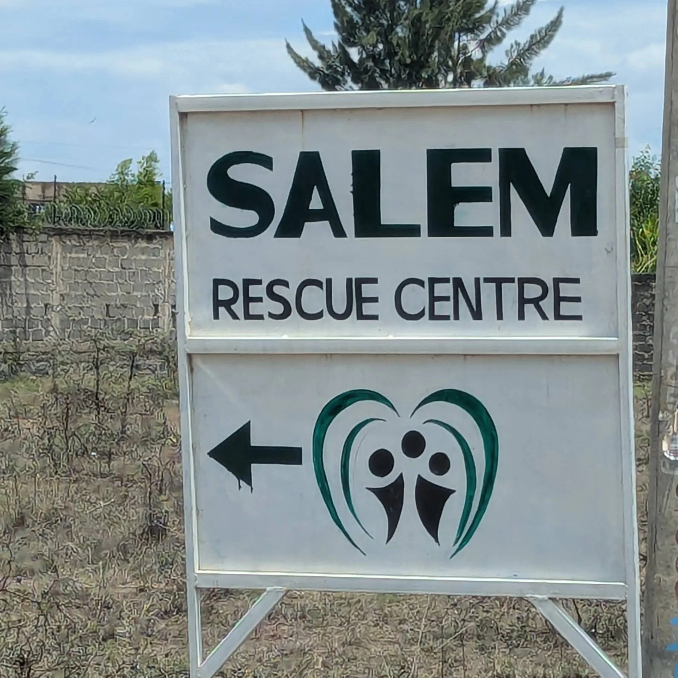 Sign for Salem Rescue Centre with an arrow pointing left and a logo featuring two stylized human figures inside a heart shape.
