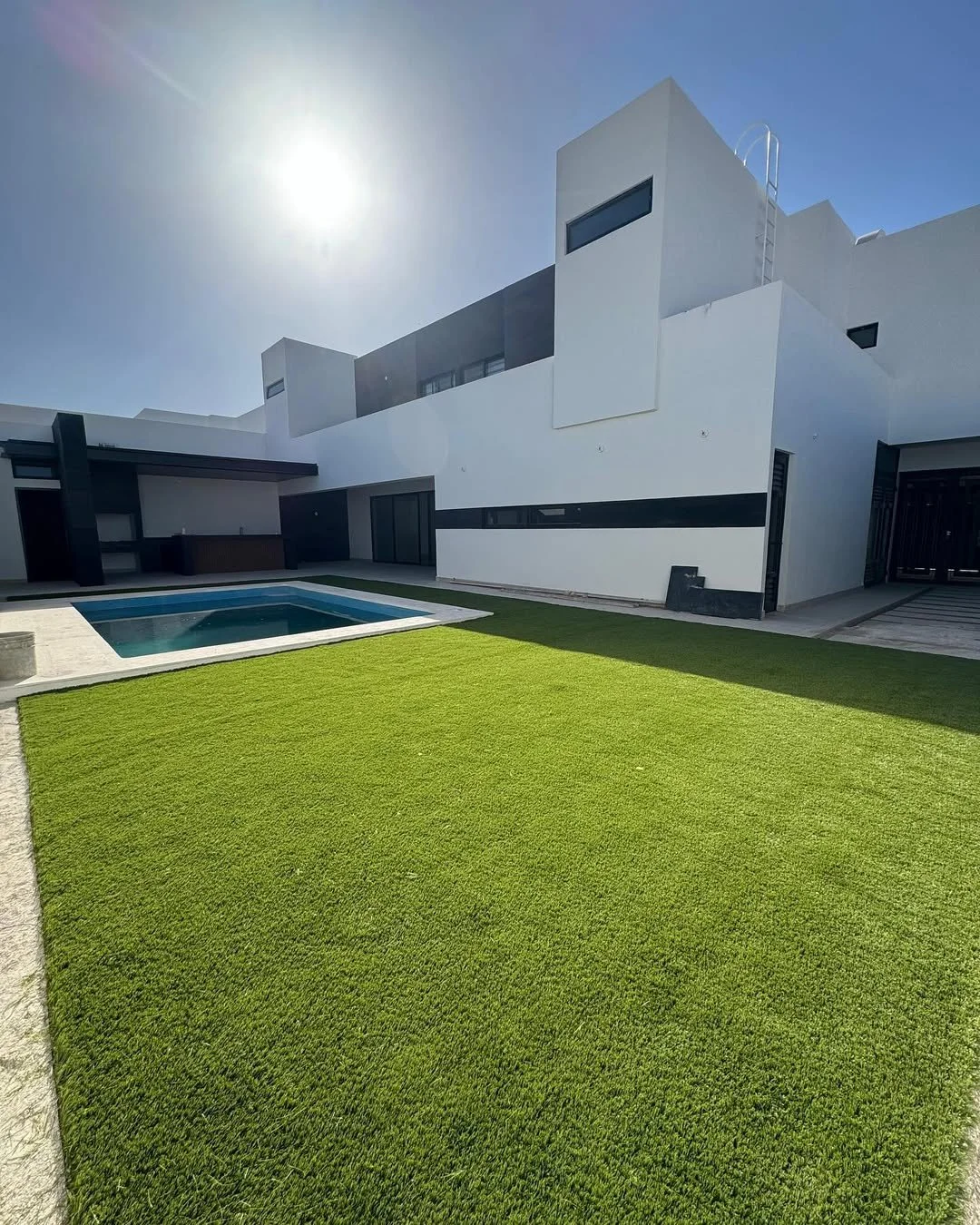 Casa moderna con jardín y piscina bajo sol