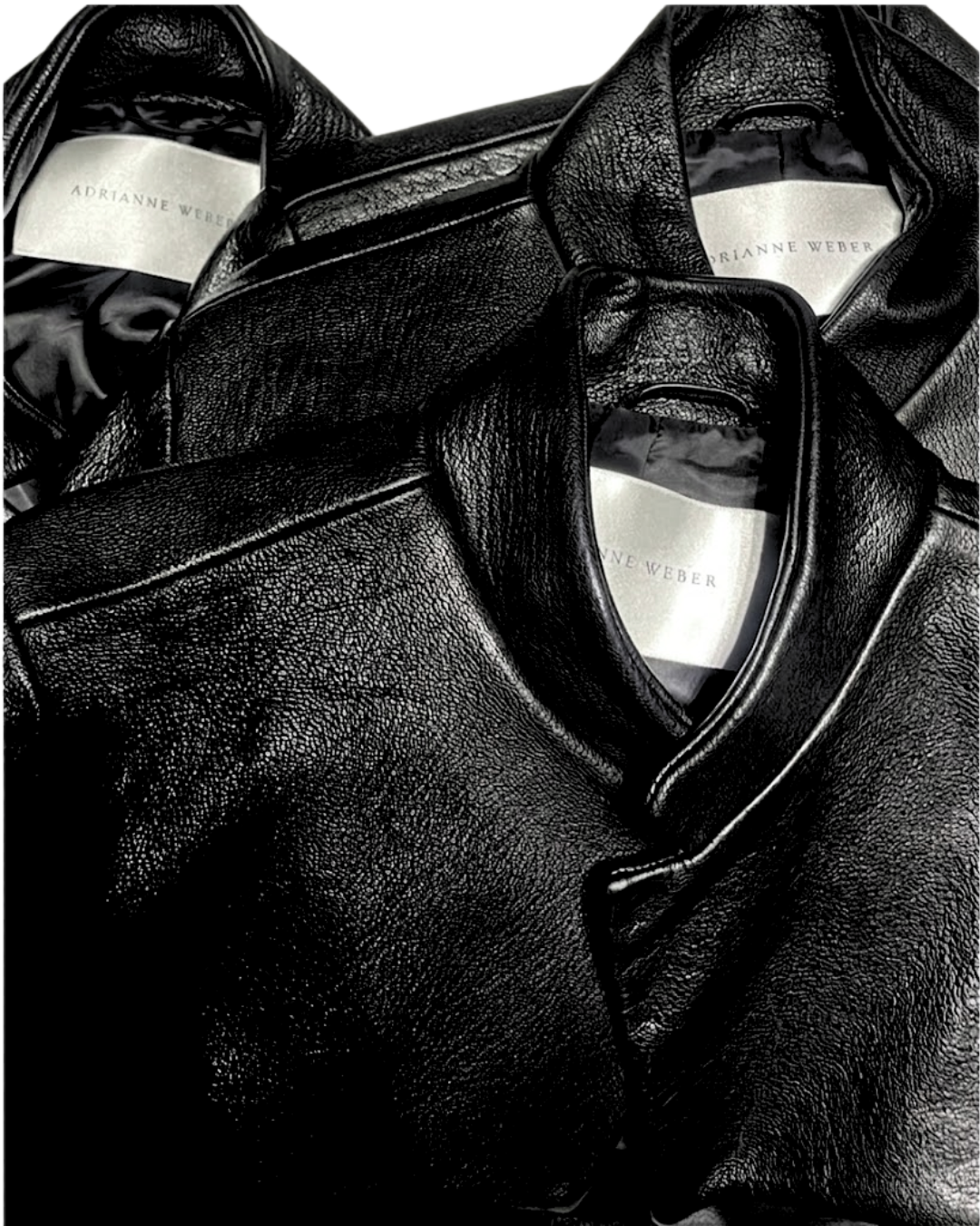 Close-up of three black leather jackets with white labels reading "Adrianne Weber."