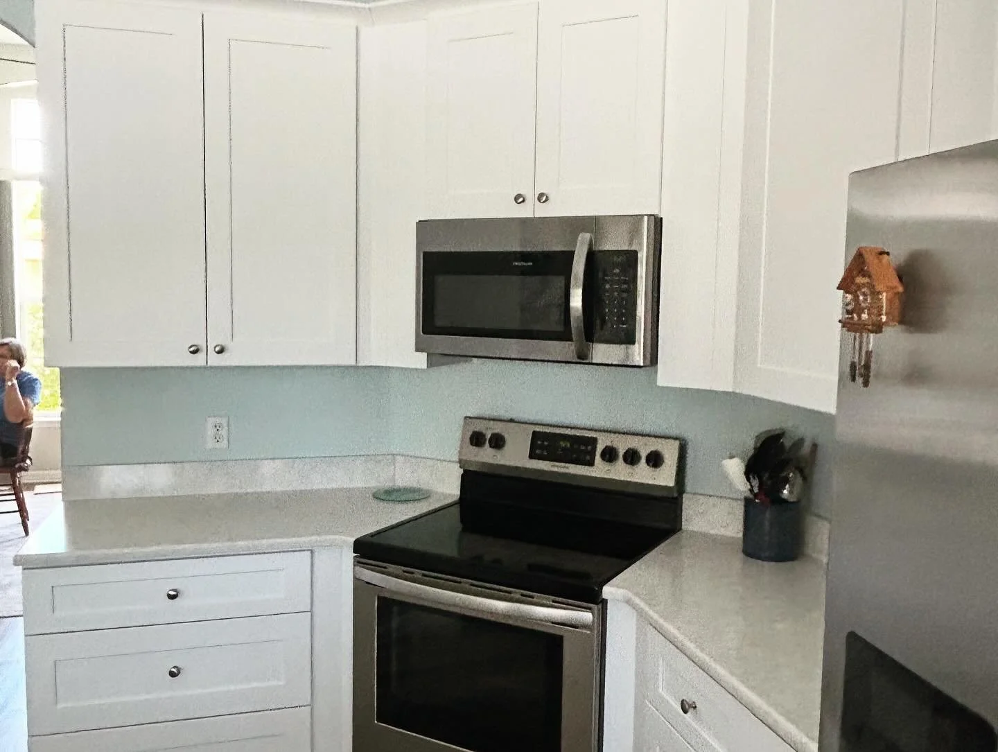 Kitchen with white cabinets, stainless steel microwave, black stove, and a light-colored countertop.