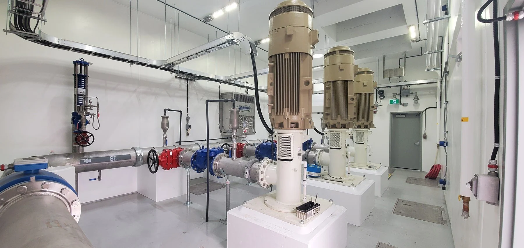 Industrial machinery in a clean room, including large vertical motors, pipes, valves, and control panels.