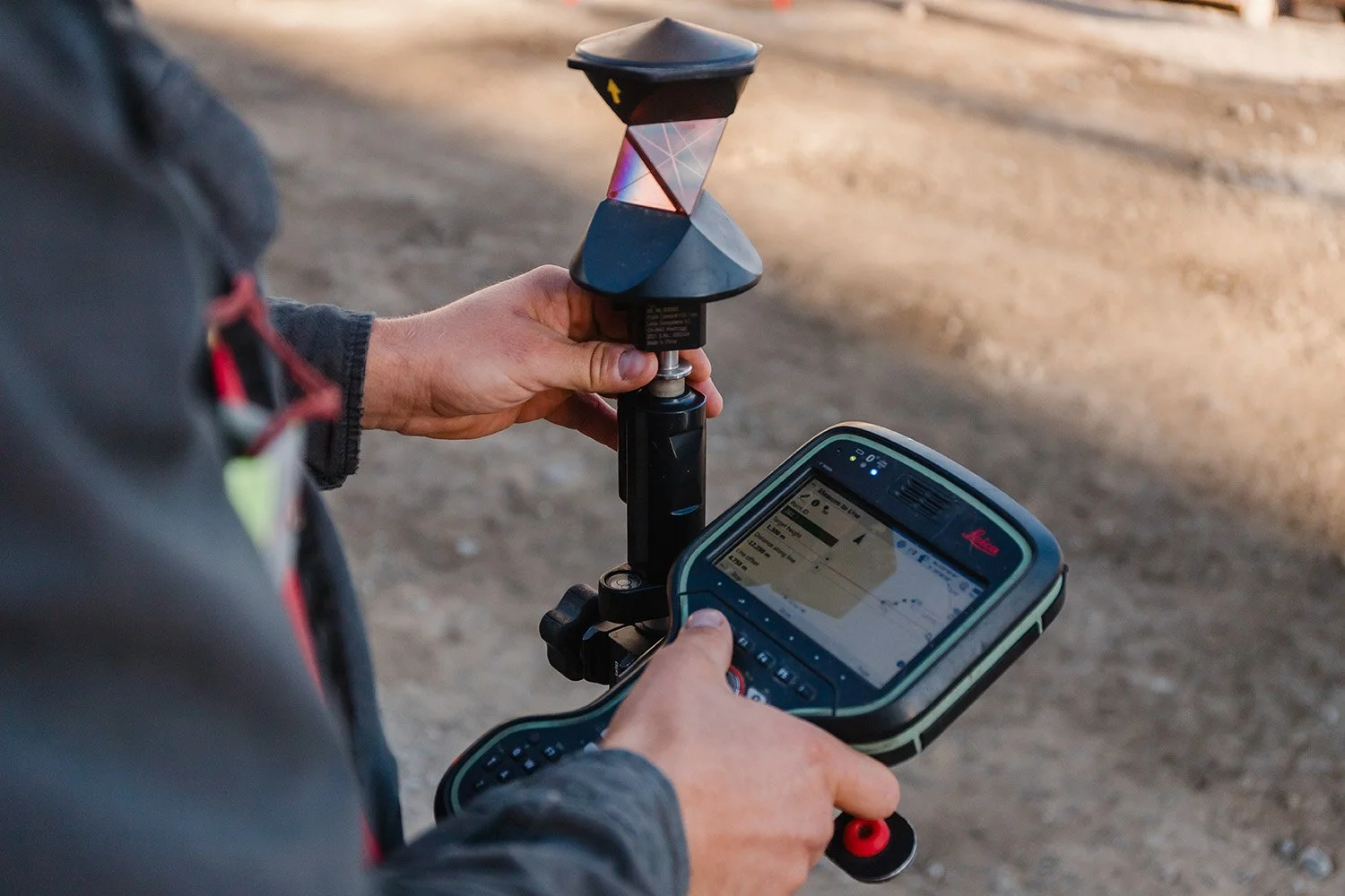 A person holding a land surveying tool outdoors.