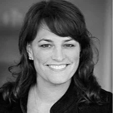 Black and white photo of a smiling woman with dark hair and earrings.