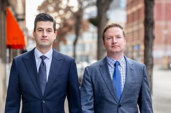 Two men in business suits walking outdoors on a city street.