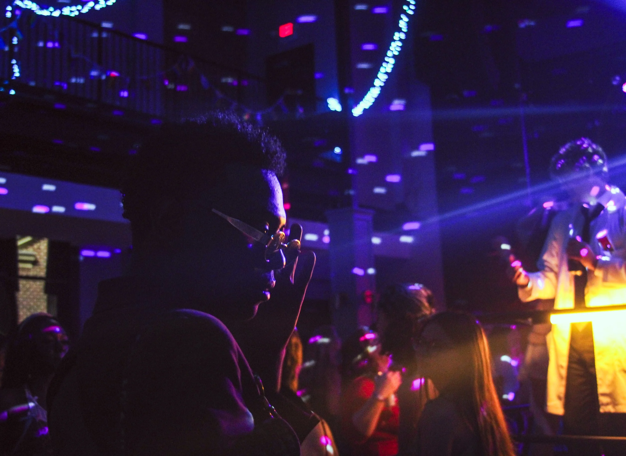 A person is illuminated by purple concert lighting.