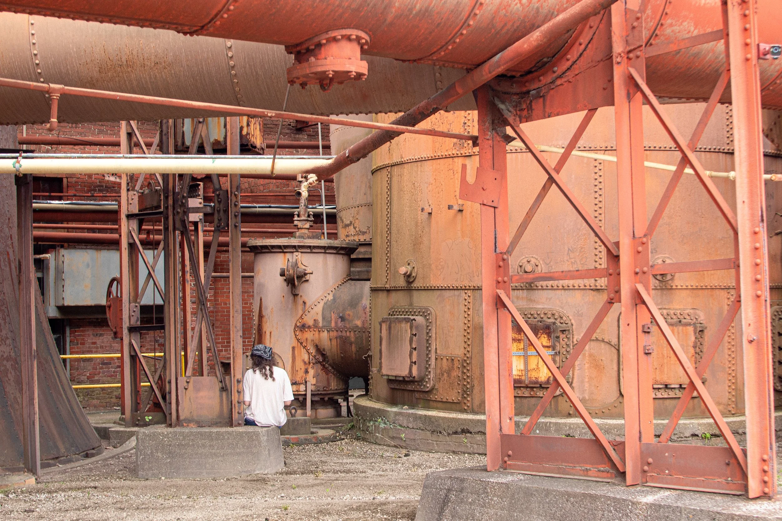 A person sits in a rusty industrial scene.