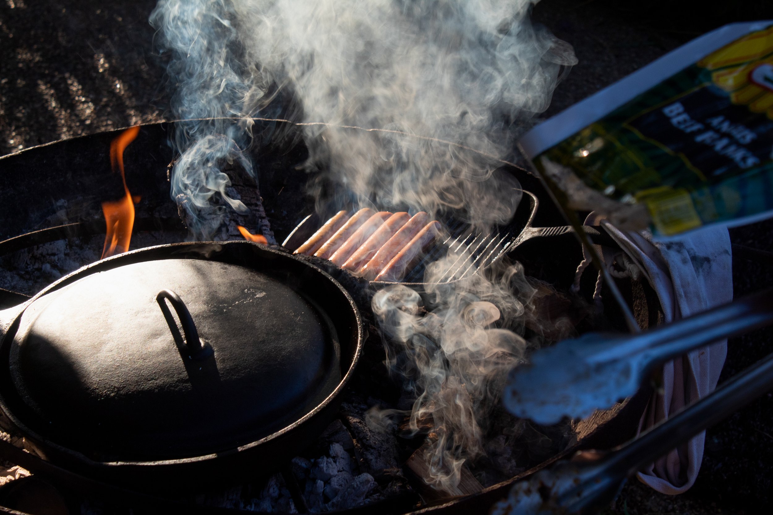 Hot dogs sizzle over a fire.