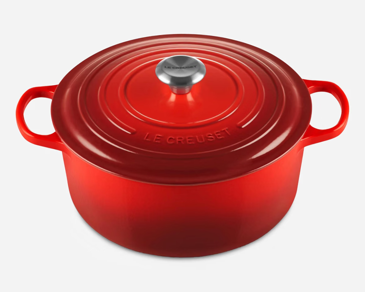 Red enameled cast iron Le Creuset Dutch oven with lid, two side handles, and silver knob on the lid.