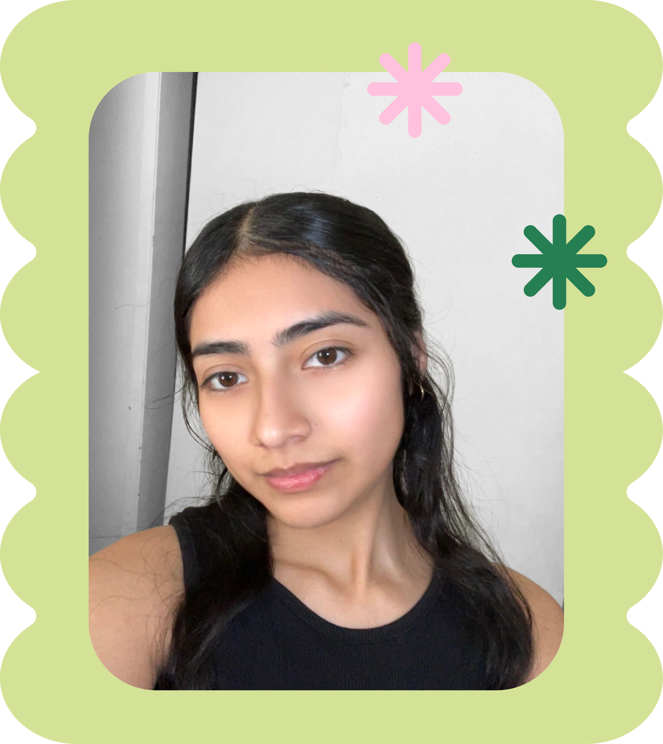 Close-up of a young woman with long dark hair, wearing a black sleeveless top, looking at the camera with a neutral expression in front of a light background.