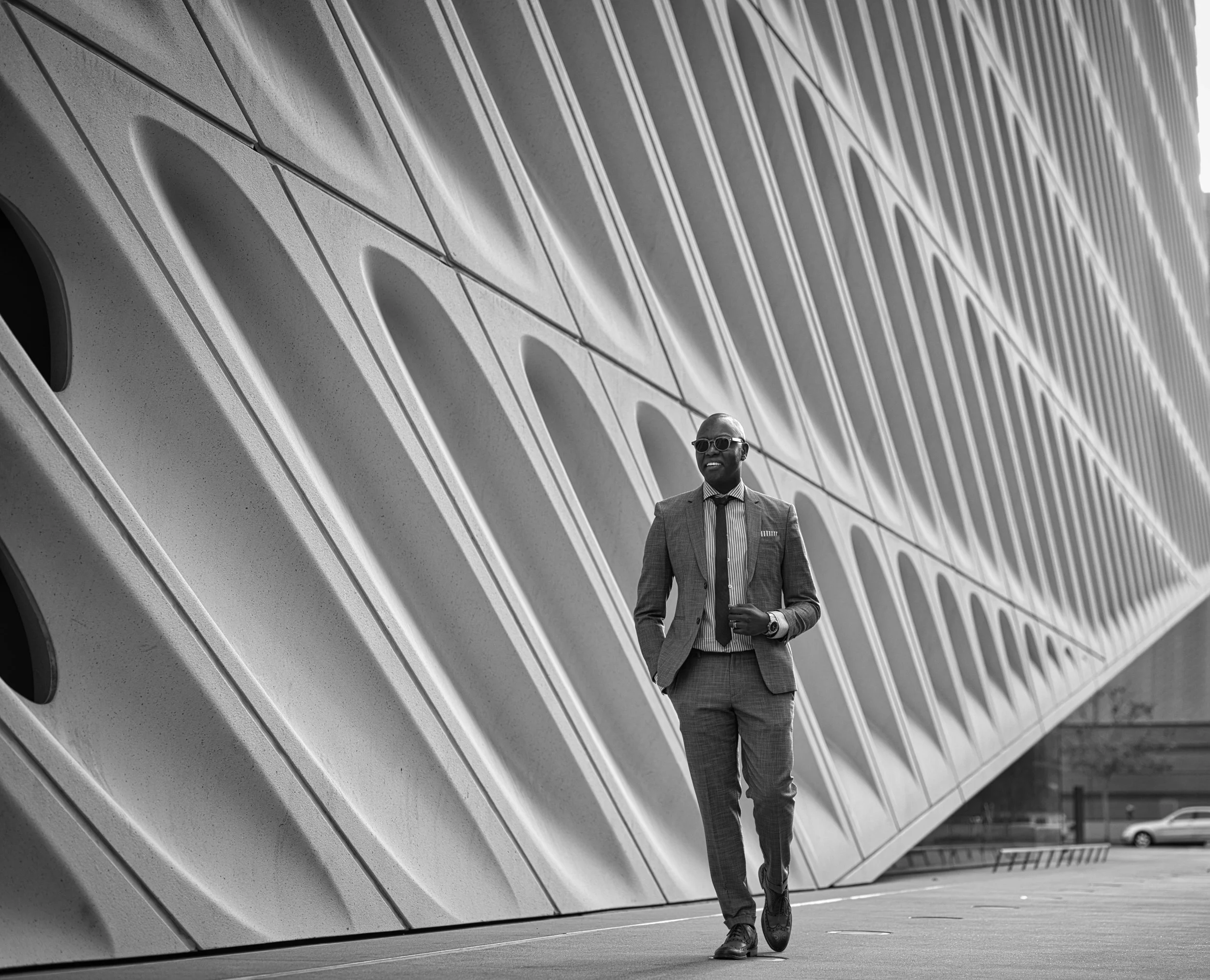 A potential Executive Job Search Candidate of Huntley Consulting Group showing a man in a business suit walking past a modern architectural building with a geometric pattern.