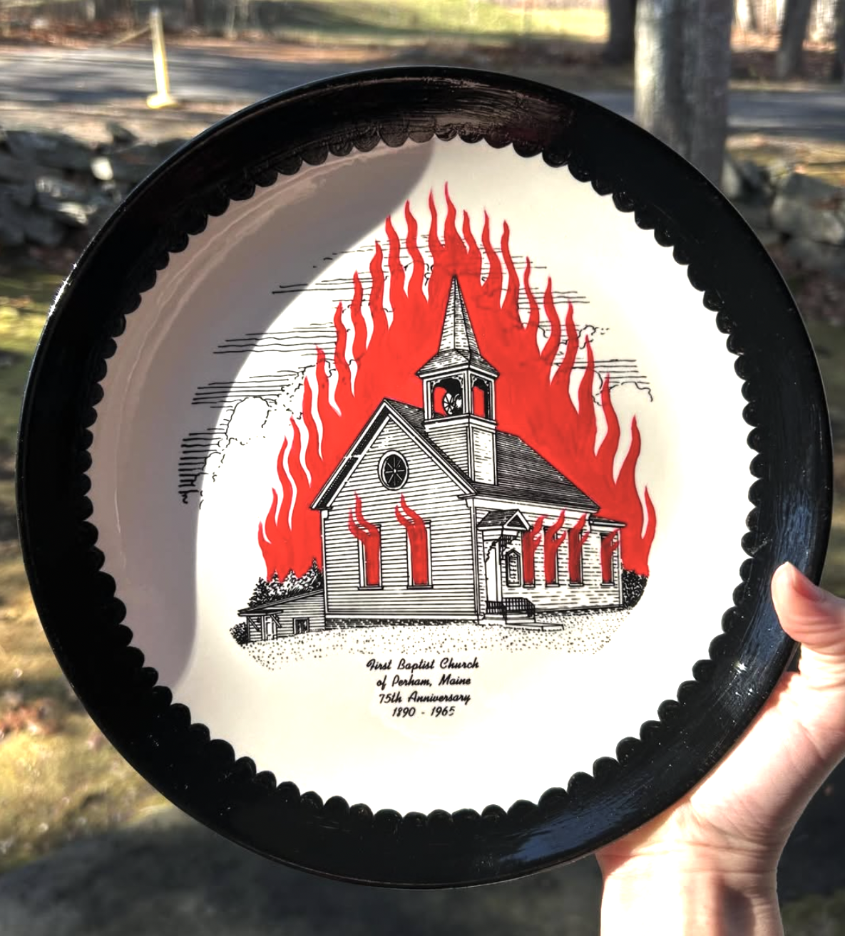 Decorative upcycled plate showing a church surrounded by red flames.