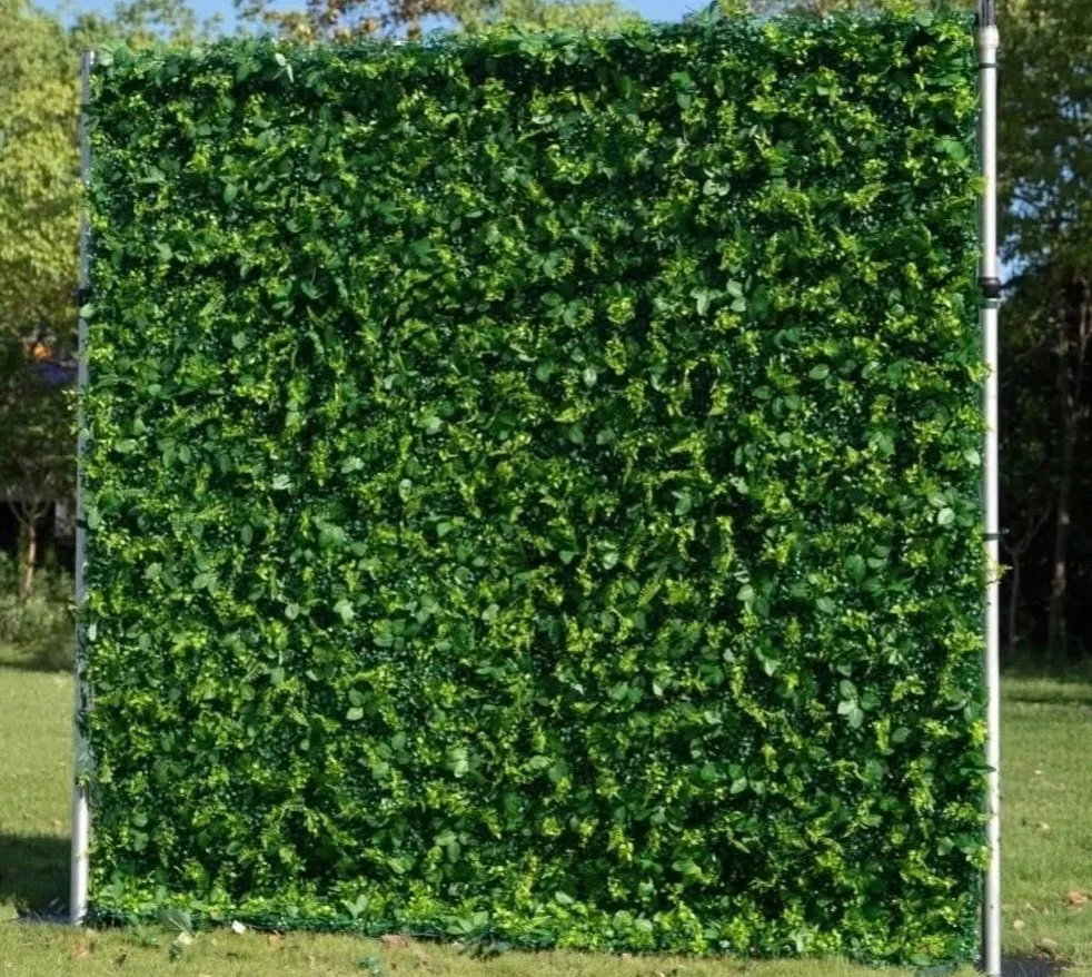 A square panel covered entirely with dense green leaves, framed by a metal structure, outdoors with grass and trees in the background.