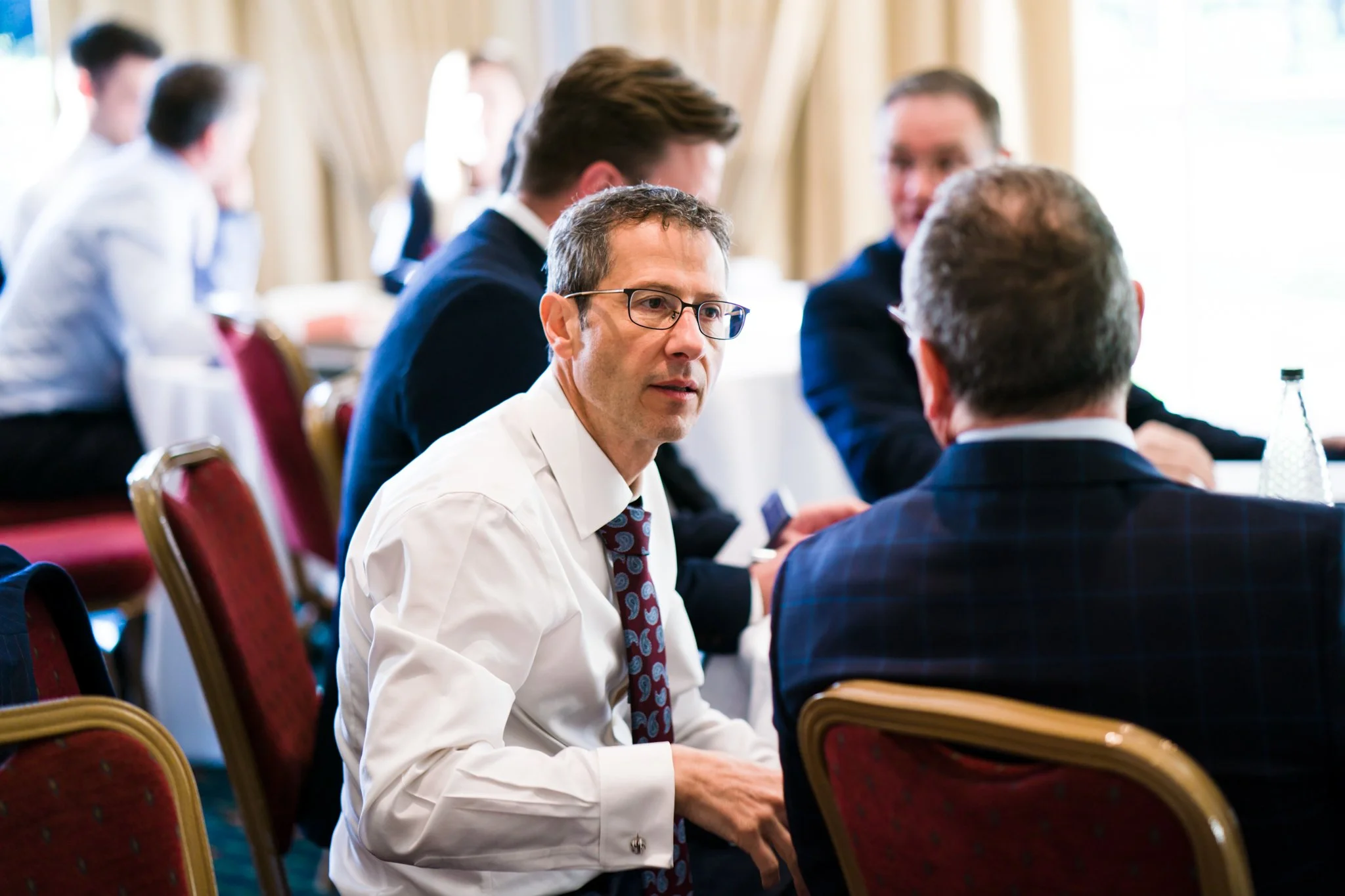 Business professionals engaged in conversation during a meeting in a formal conference room.
