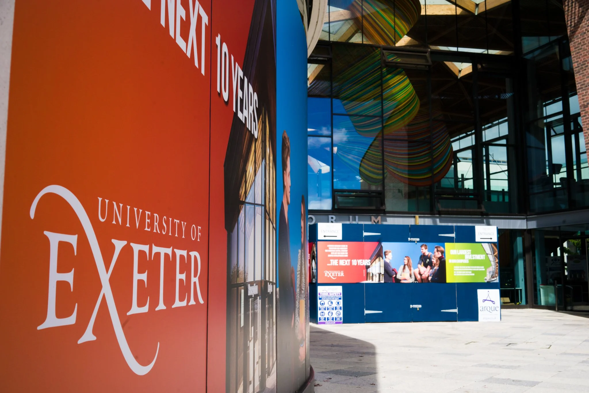 Exterior view of the University of Exeter campus entrance with promotional banners and colorful artwork inside the building.
