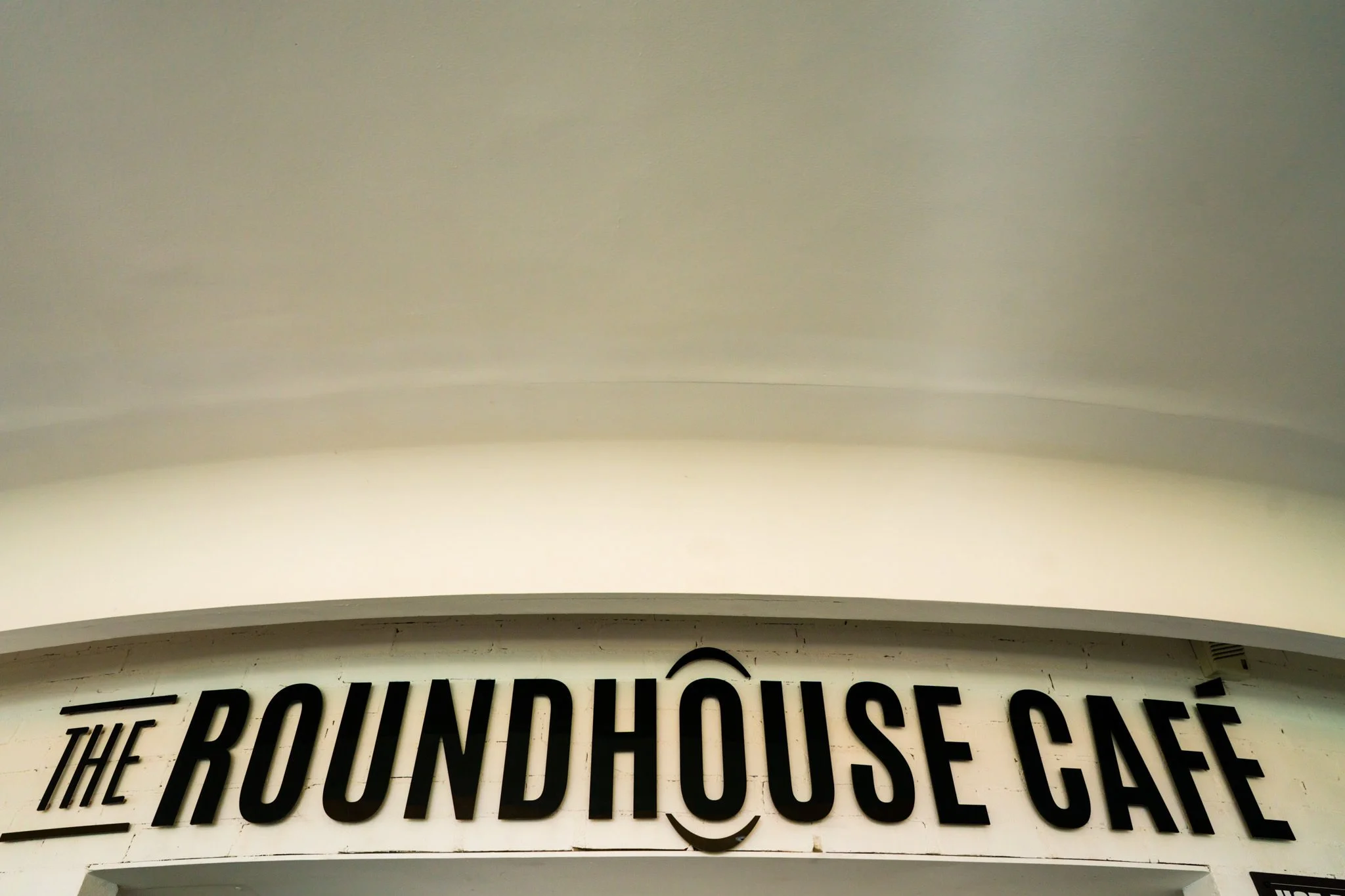 Sign for The Roundhouse Café with bold black letters on a white background.