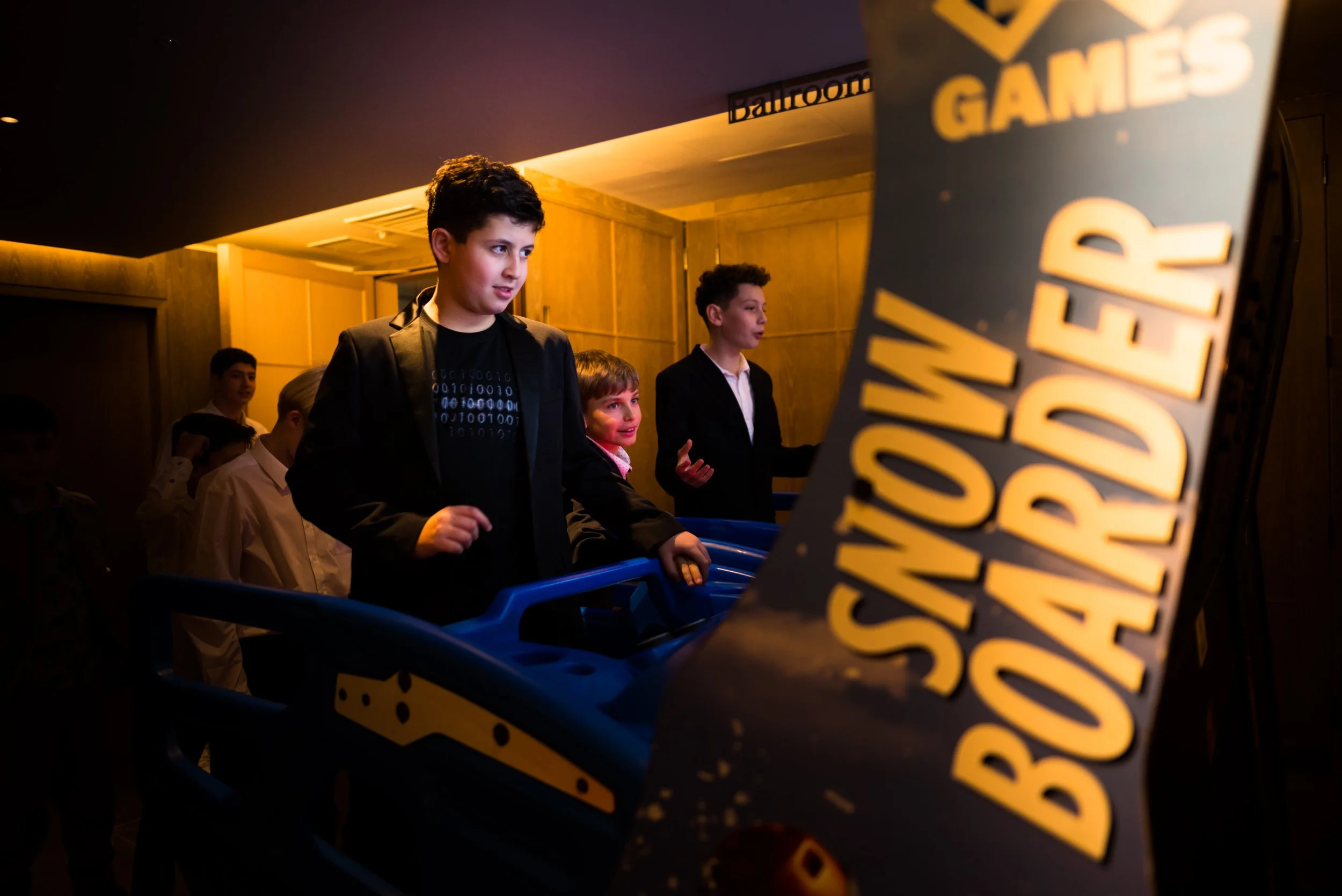 Young boys playing an arcade game called 'Showdown Boss Battle' in a dimly lit arcade.