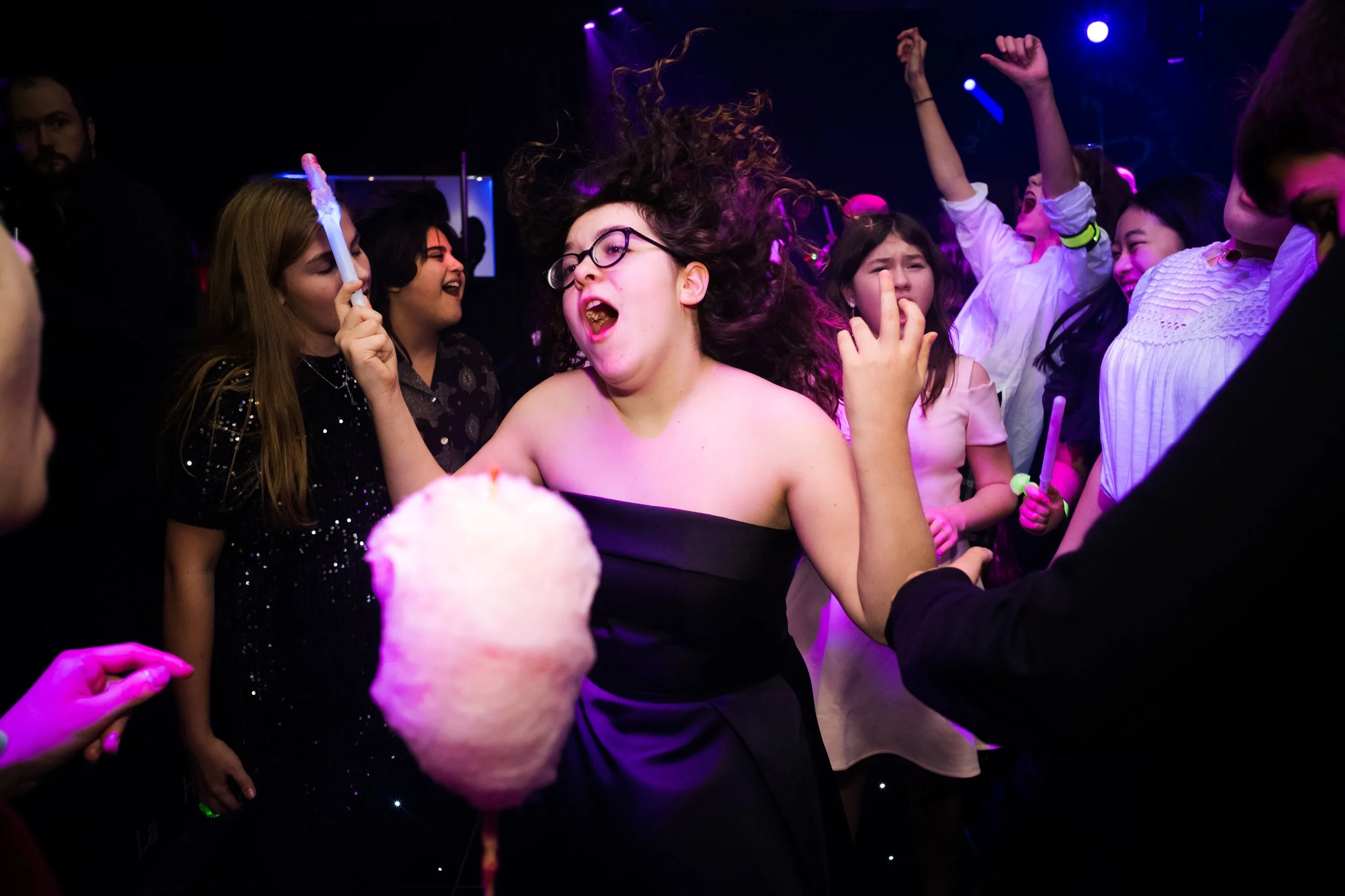 People dancing and celebrating at a party with colorful lighting.