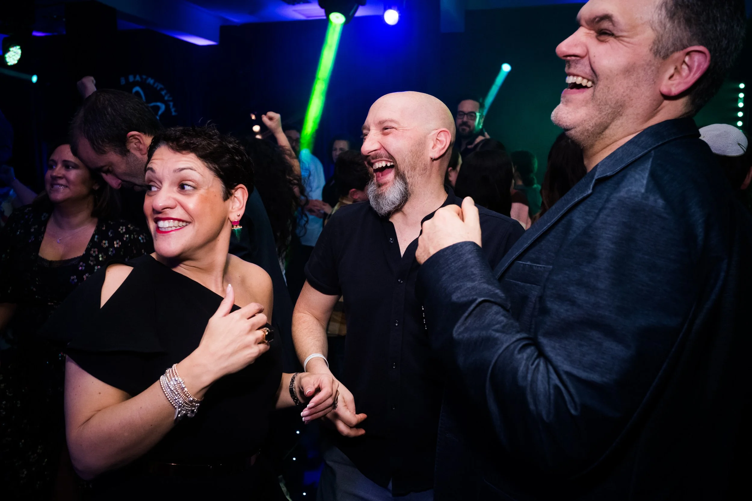 People dancing and enjoying themselves at a lively party or club with colorful lights.