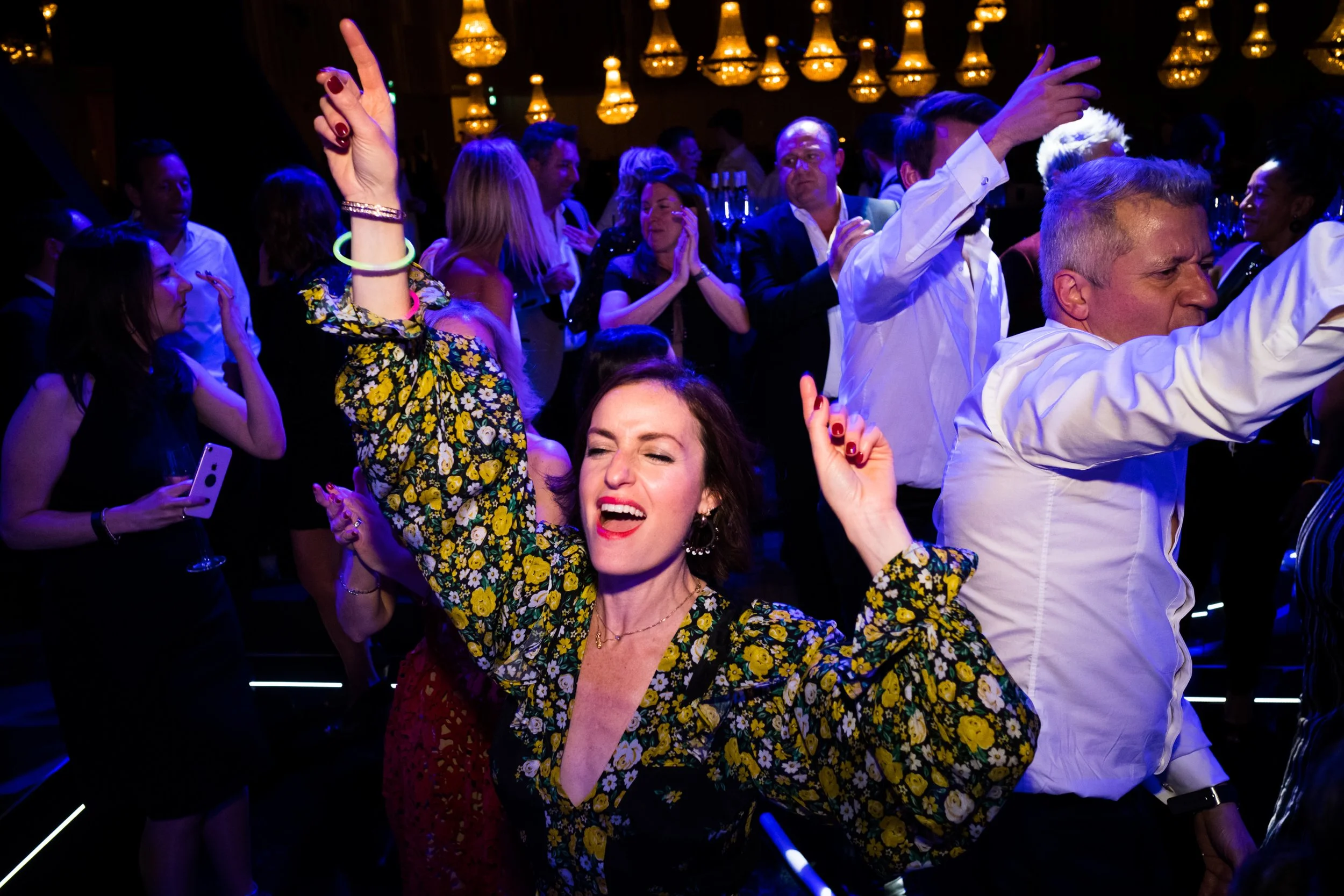 People dancing and enjoying themselves at a lively party or nightclub, with colorful lighting and a joyful atmosphere.