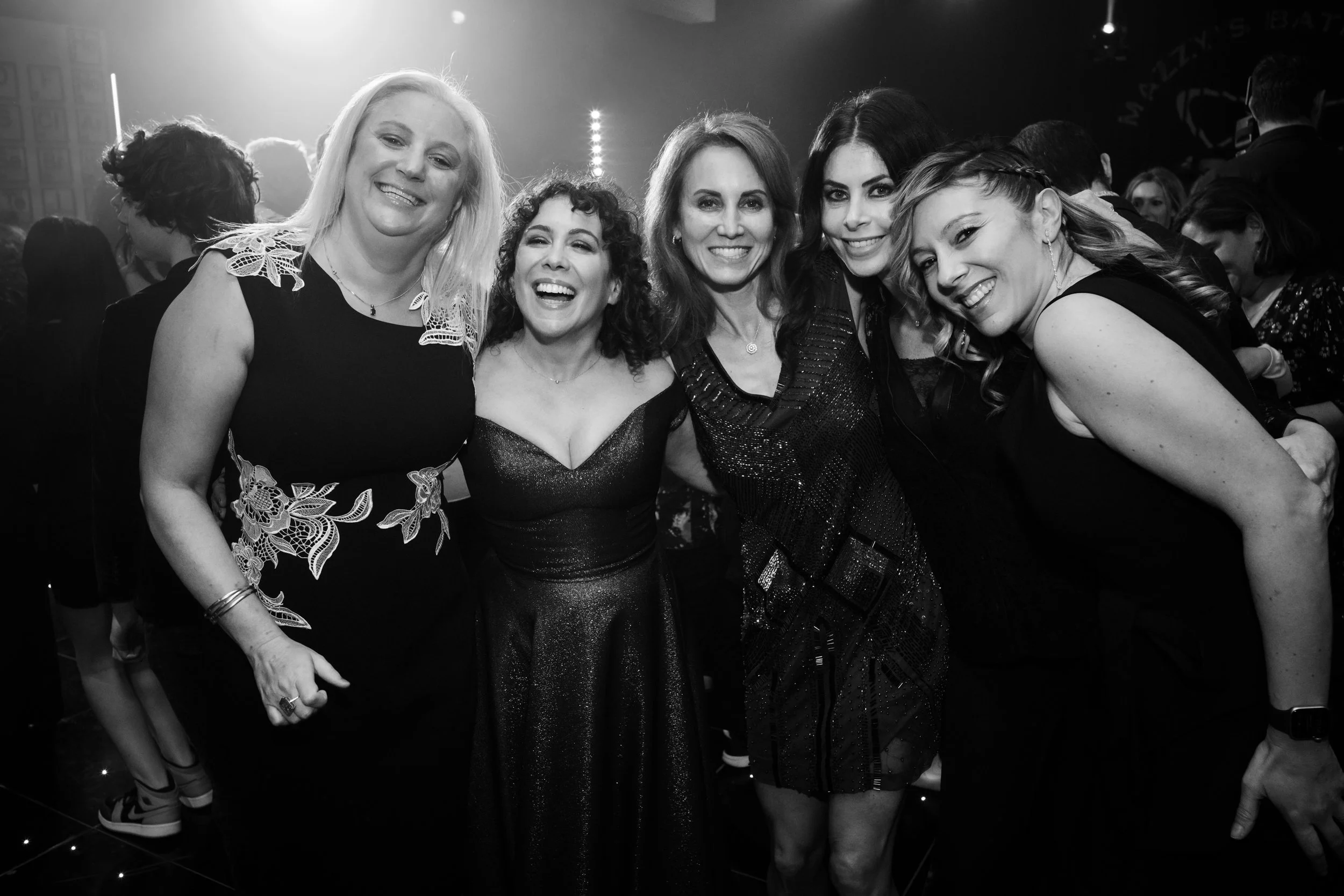 Group of five women smiling during a celebration or party at night.