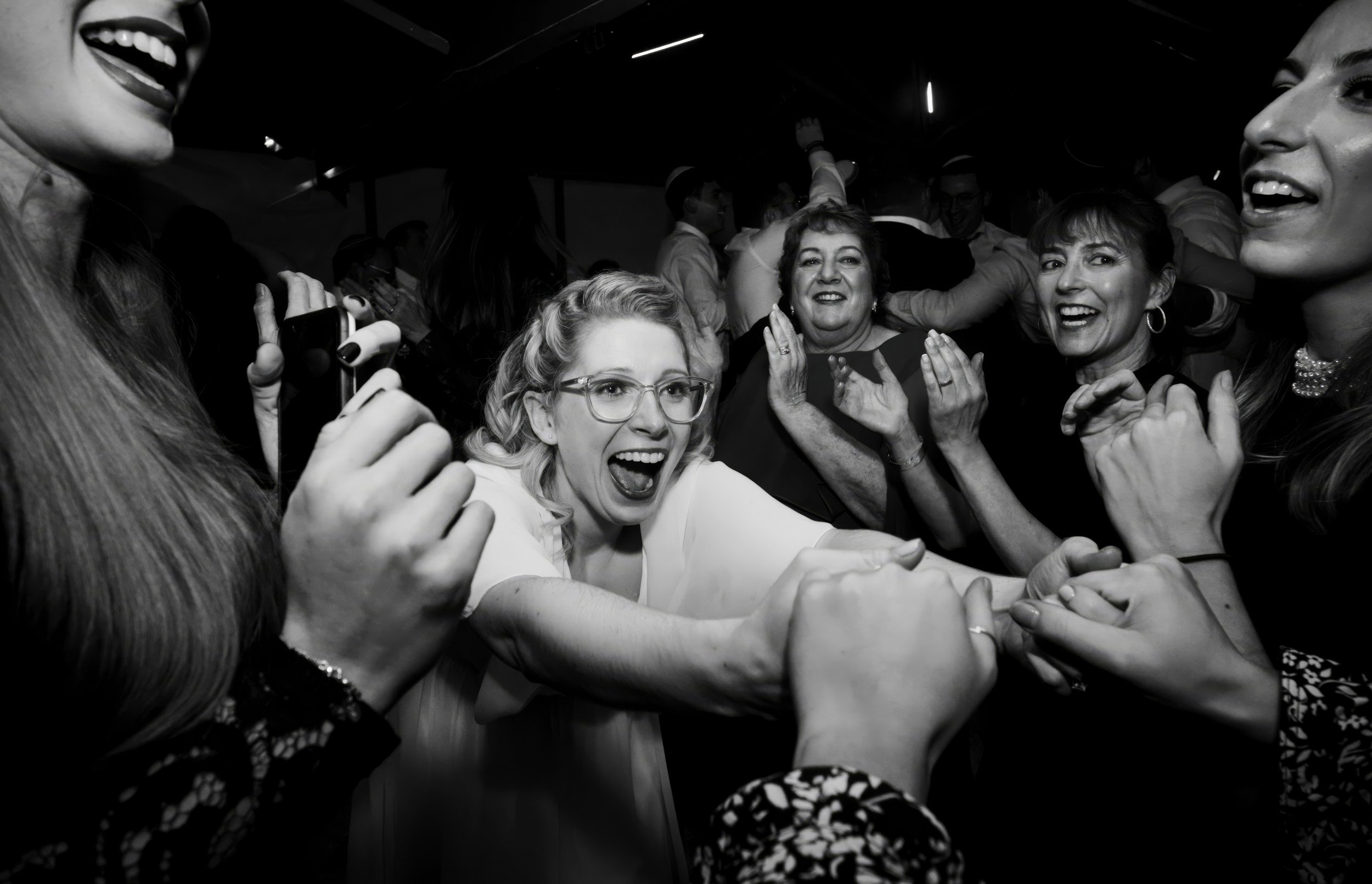 Group of women celebrating and having fun at a party or dance, with some holding hands and smiling.