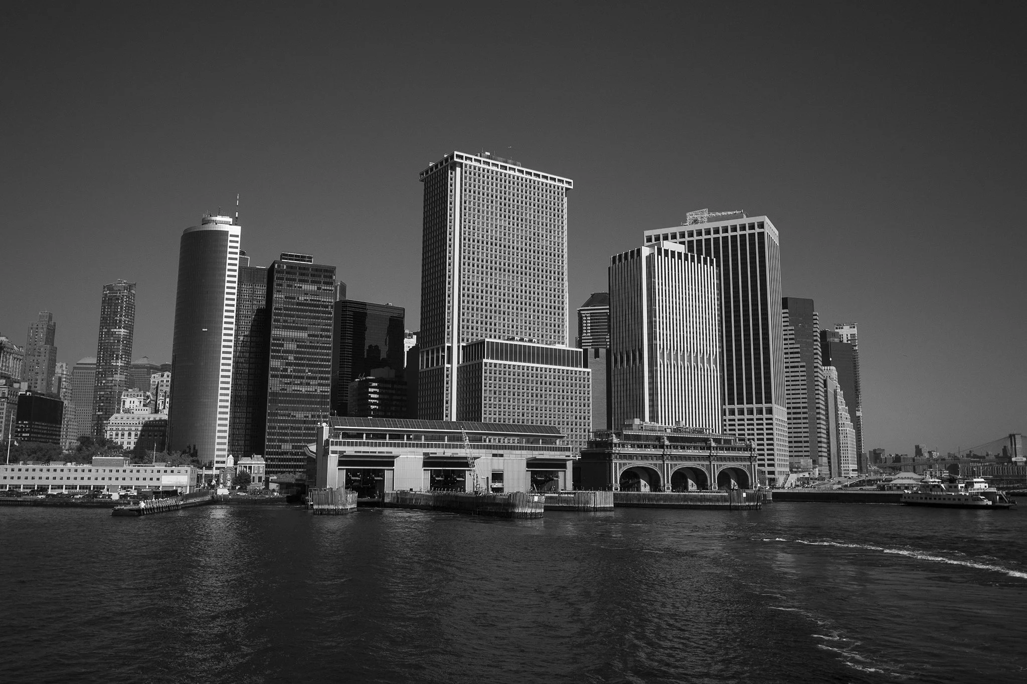 Black and white photo of a city skyline along a waterfront with high-rise buildings.