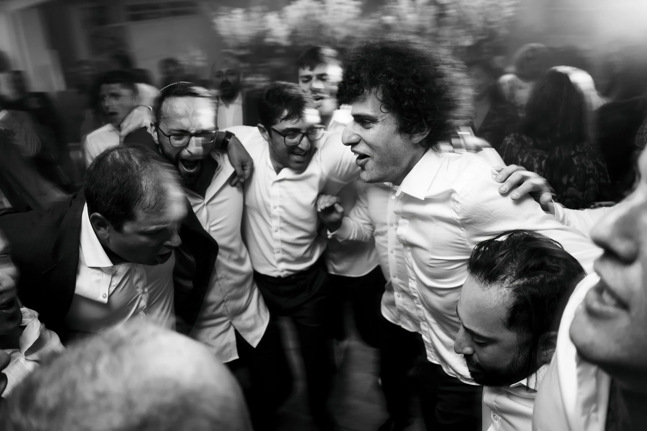 Group of people celebrating in a circle, smiling and cheering, at a party or gathering.