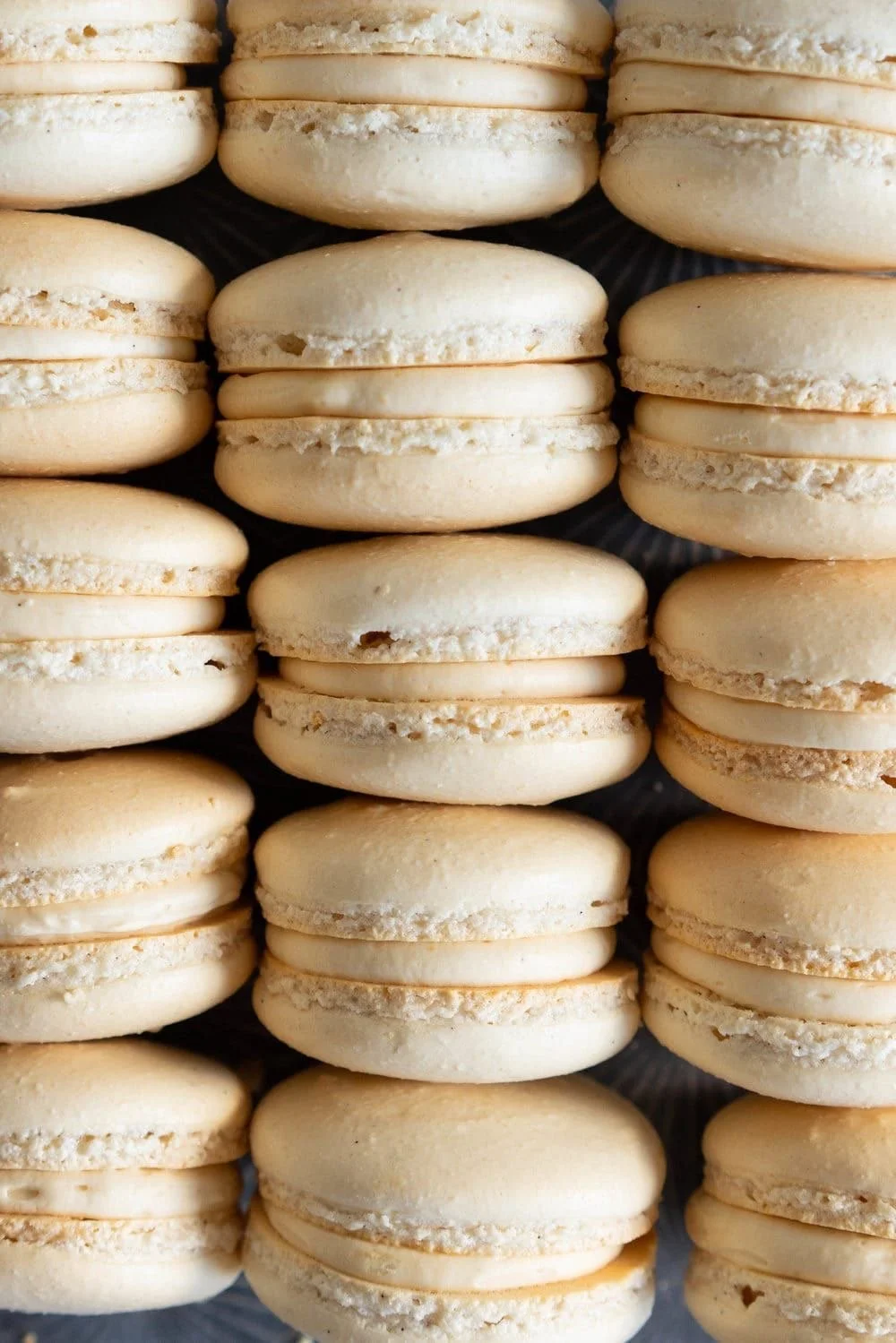 A close-up view of several vanilla macarons stacked in rows.