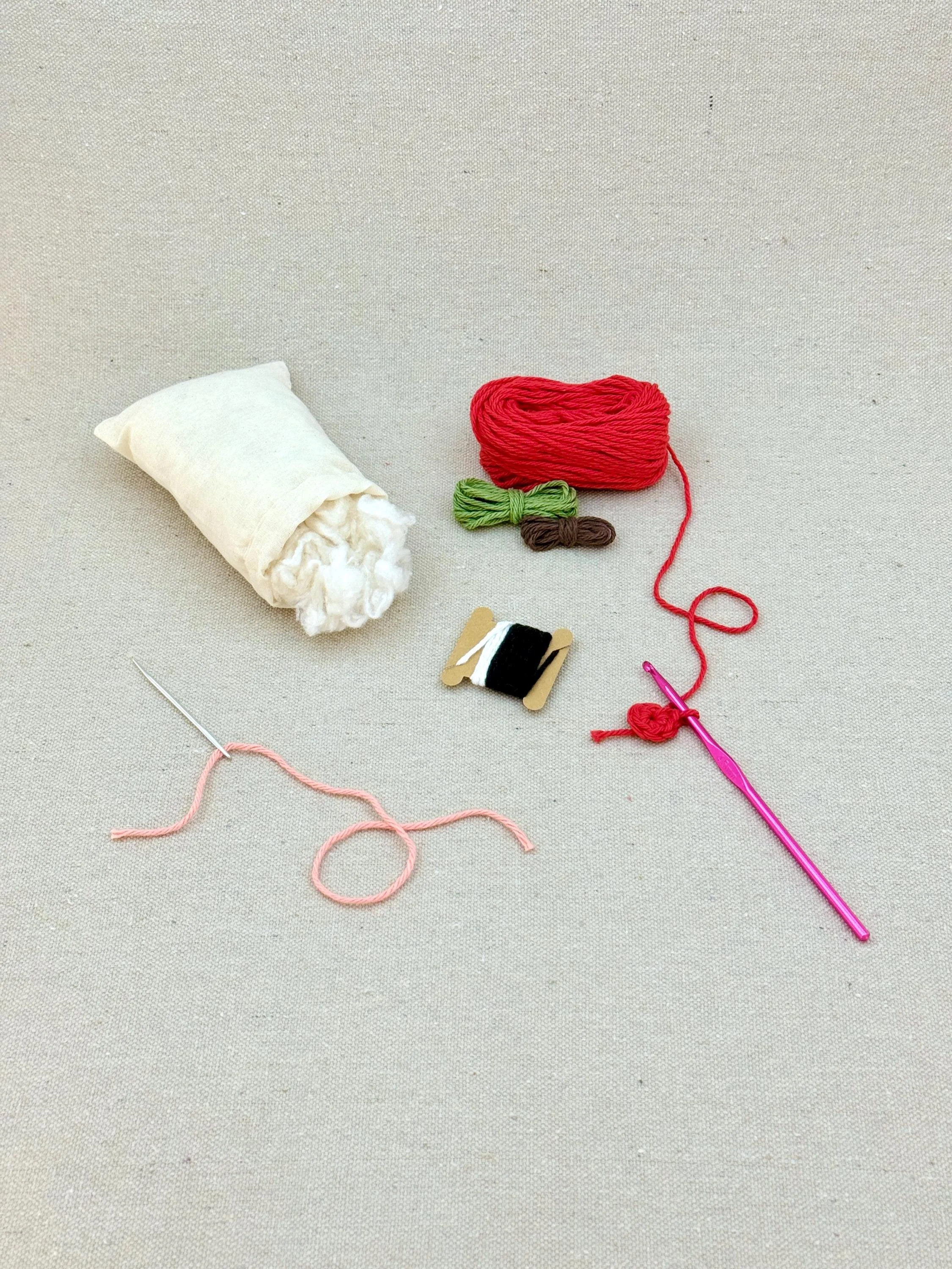 A red amigurumi apple mid project using a DIY crochet kit