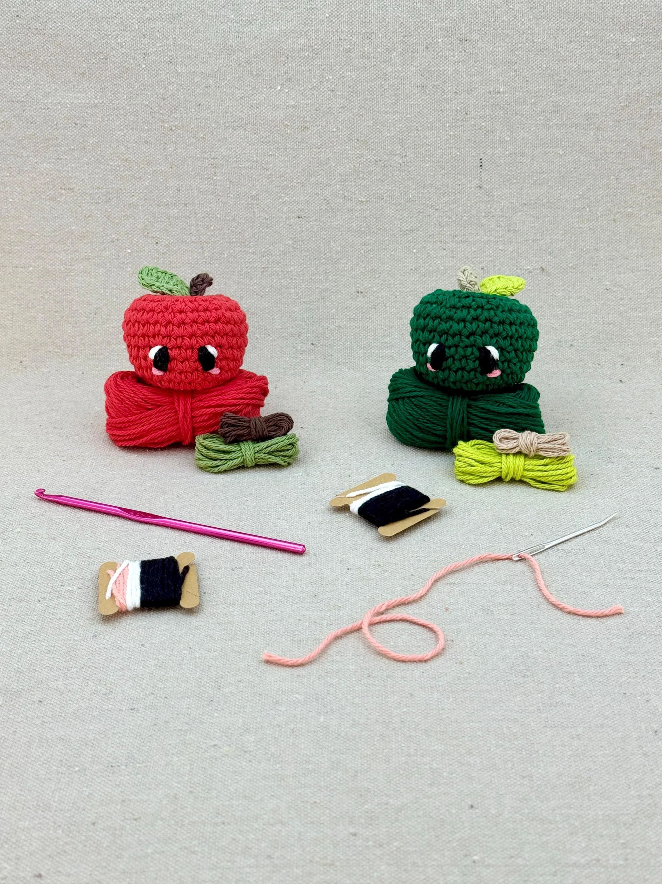 Two amigurmi apples in red and pine green on matching colour yarn