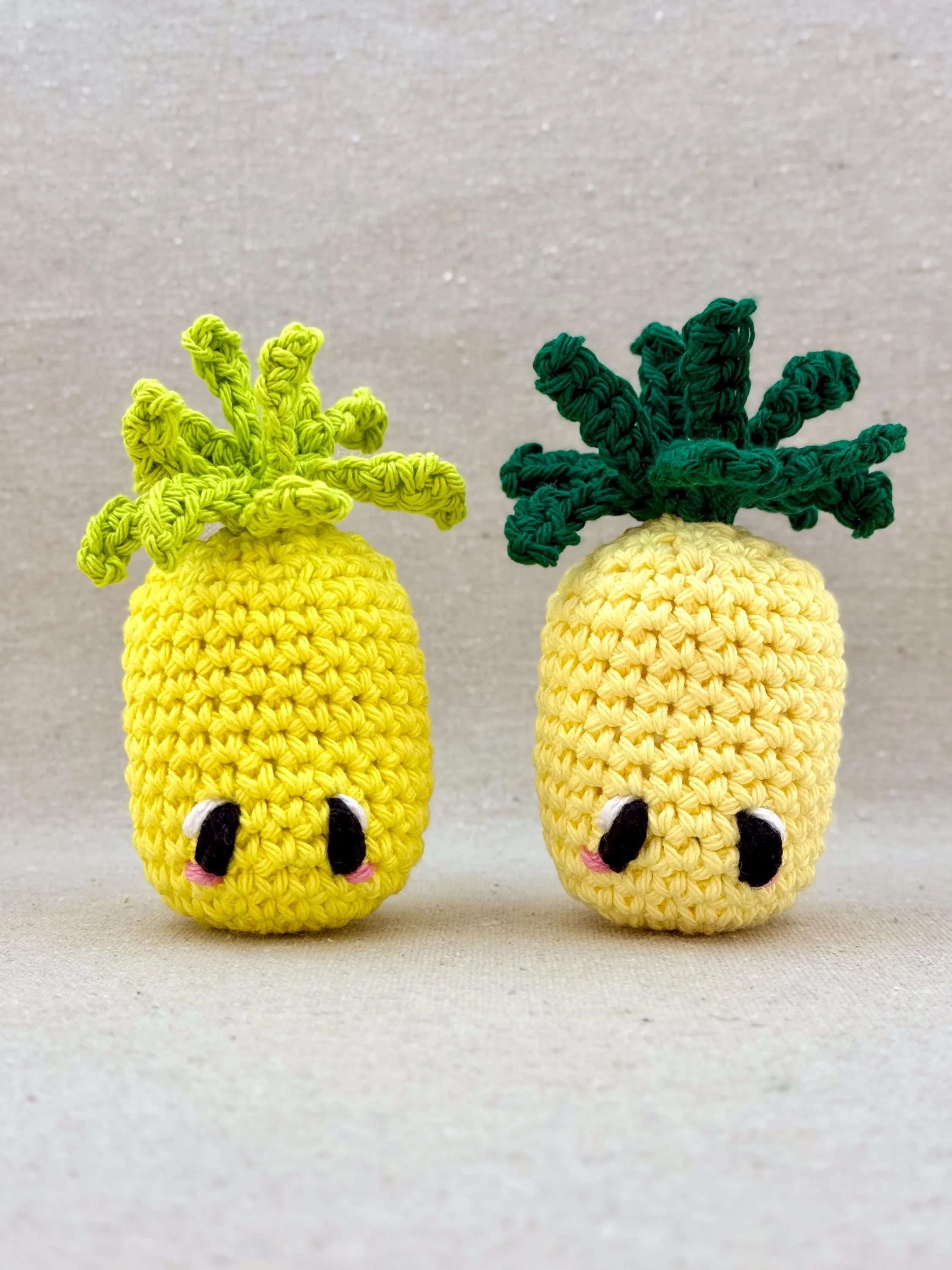 Two crochet pineapples in bright yellow and butter yellow sitting next to each other (Copy)