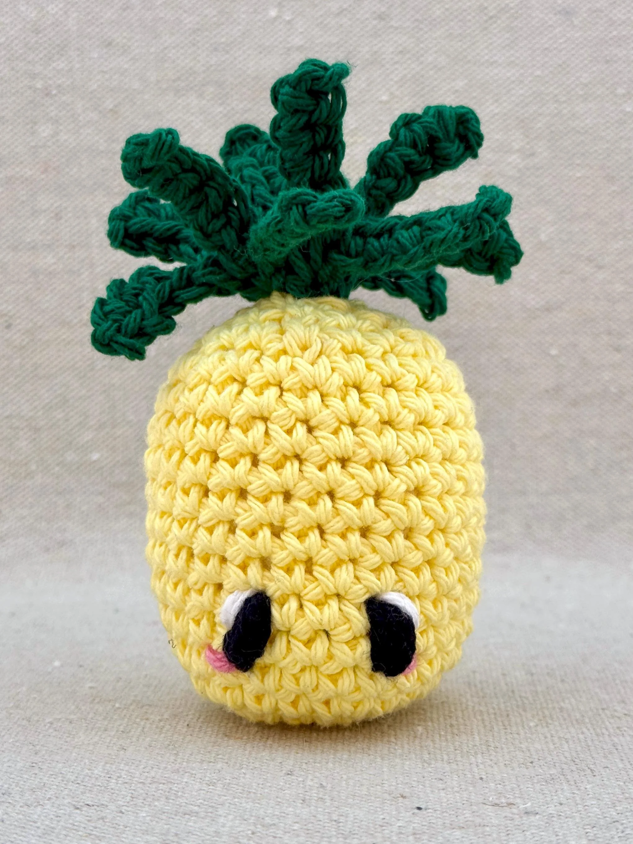 Close up of a butter yellow pineapple amigurumi plush made from cotton yarn and cotton stuffing (Copy)