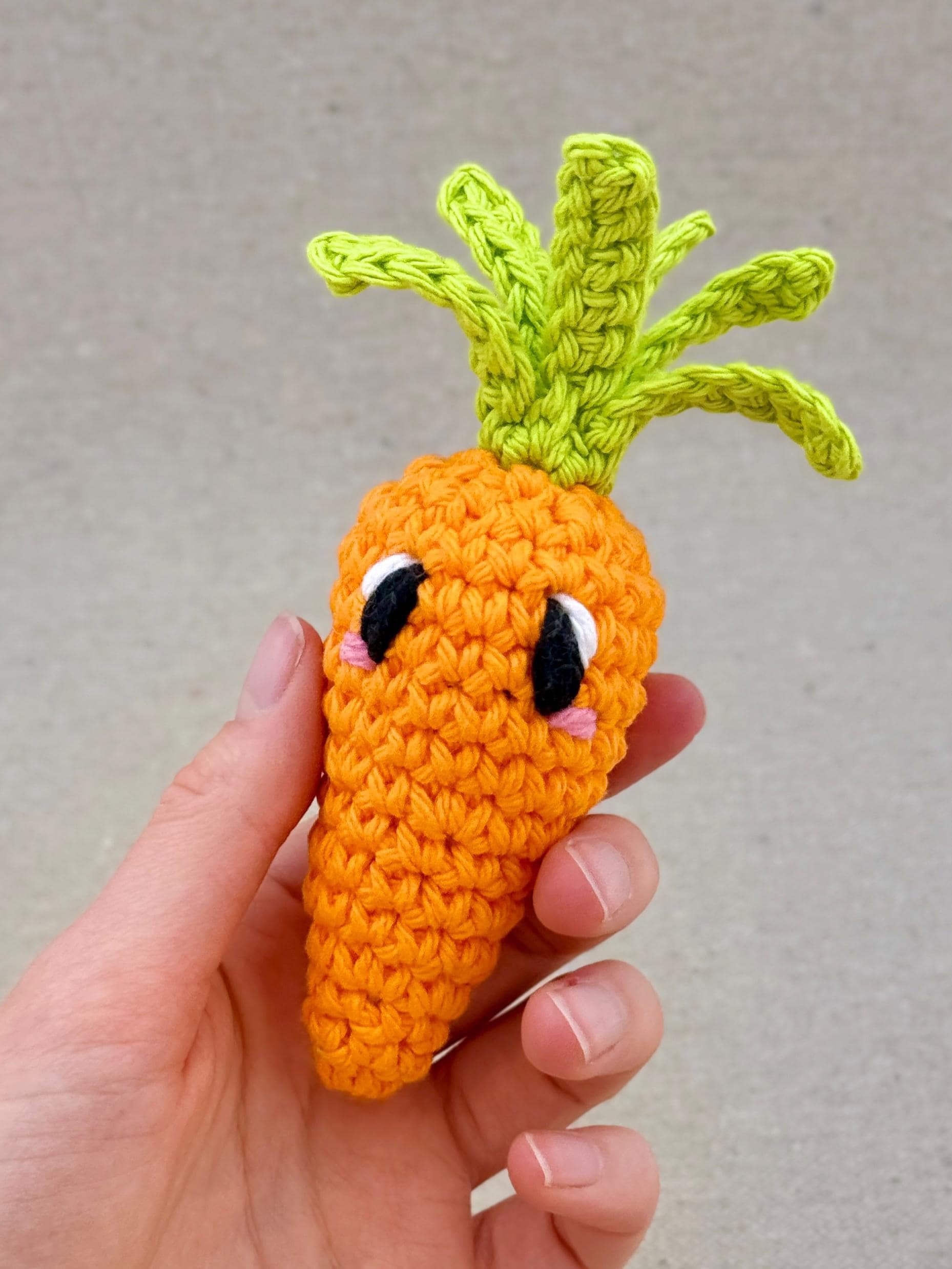 A orange crochet carrot plush held in a hand (Copy)