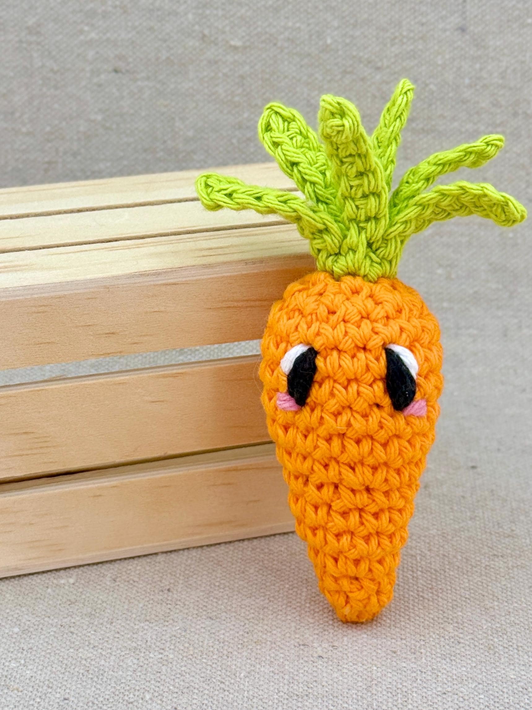 An orange amigurumi carrot plush posed with a mini wooden crate (Copy)