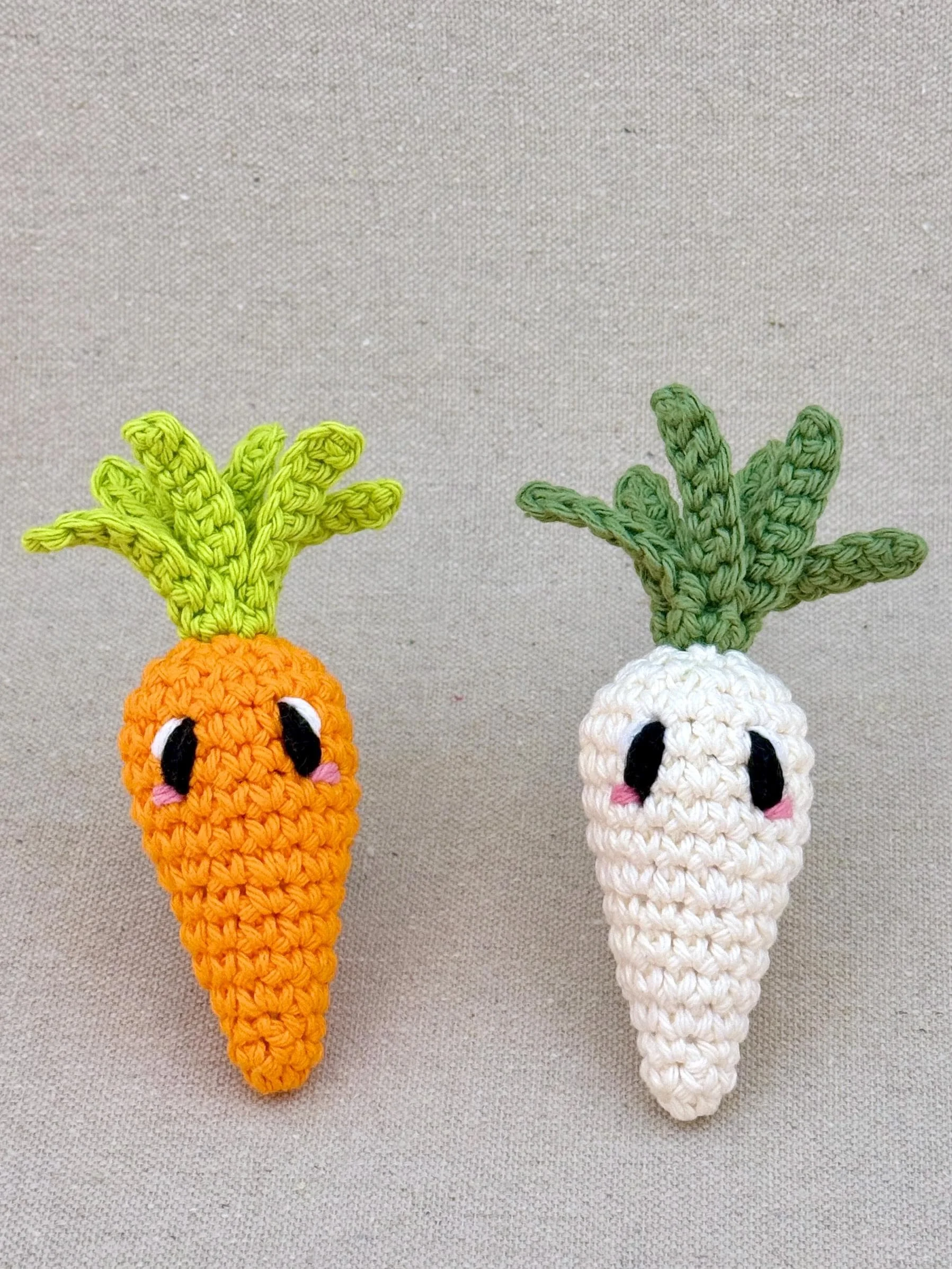Two crochet carrots in orange and cream sitting next to each other (Copy)