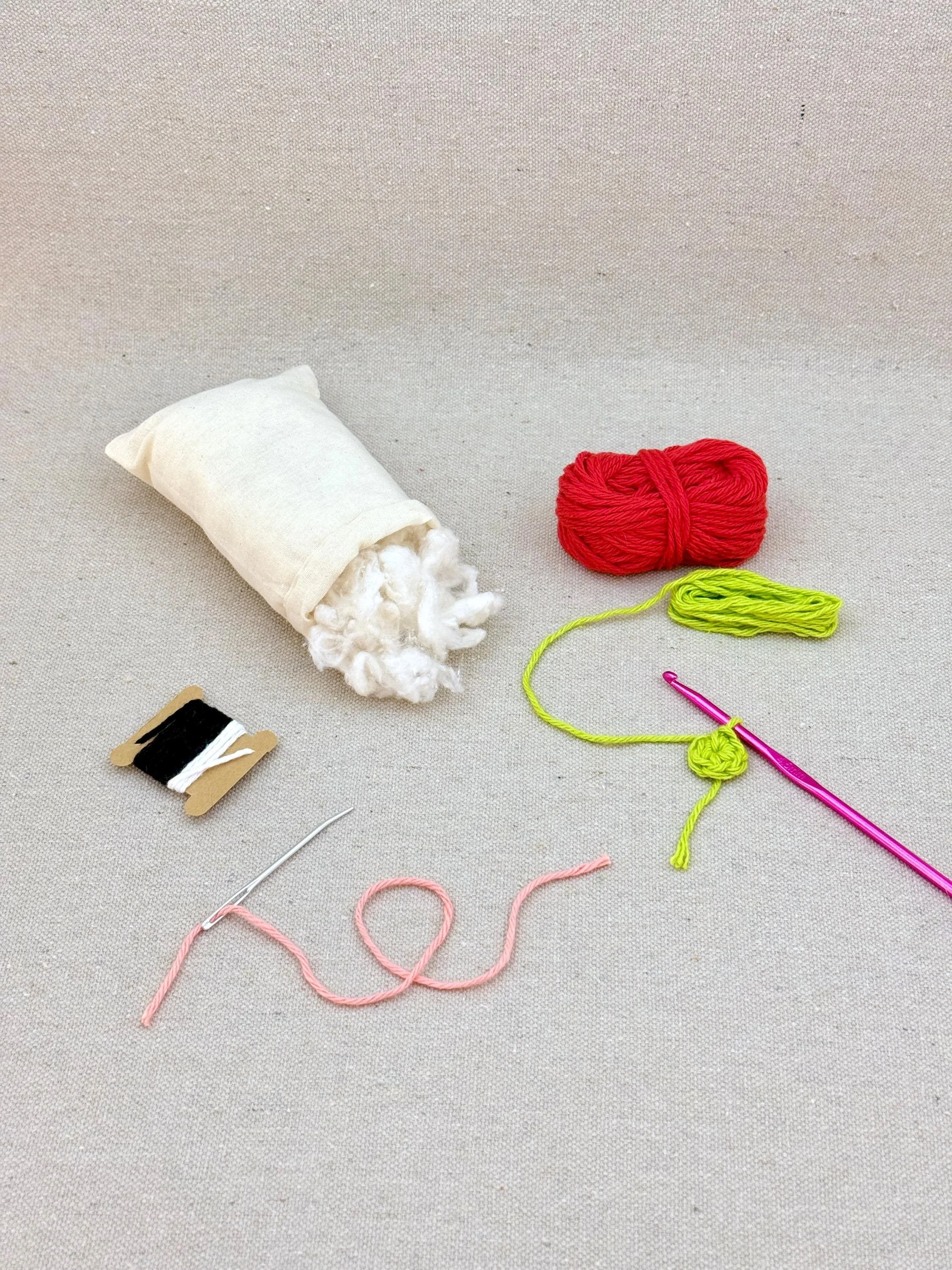 A red amigurumi tomato mid project using a DIY crochet kit