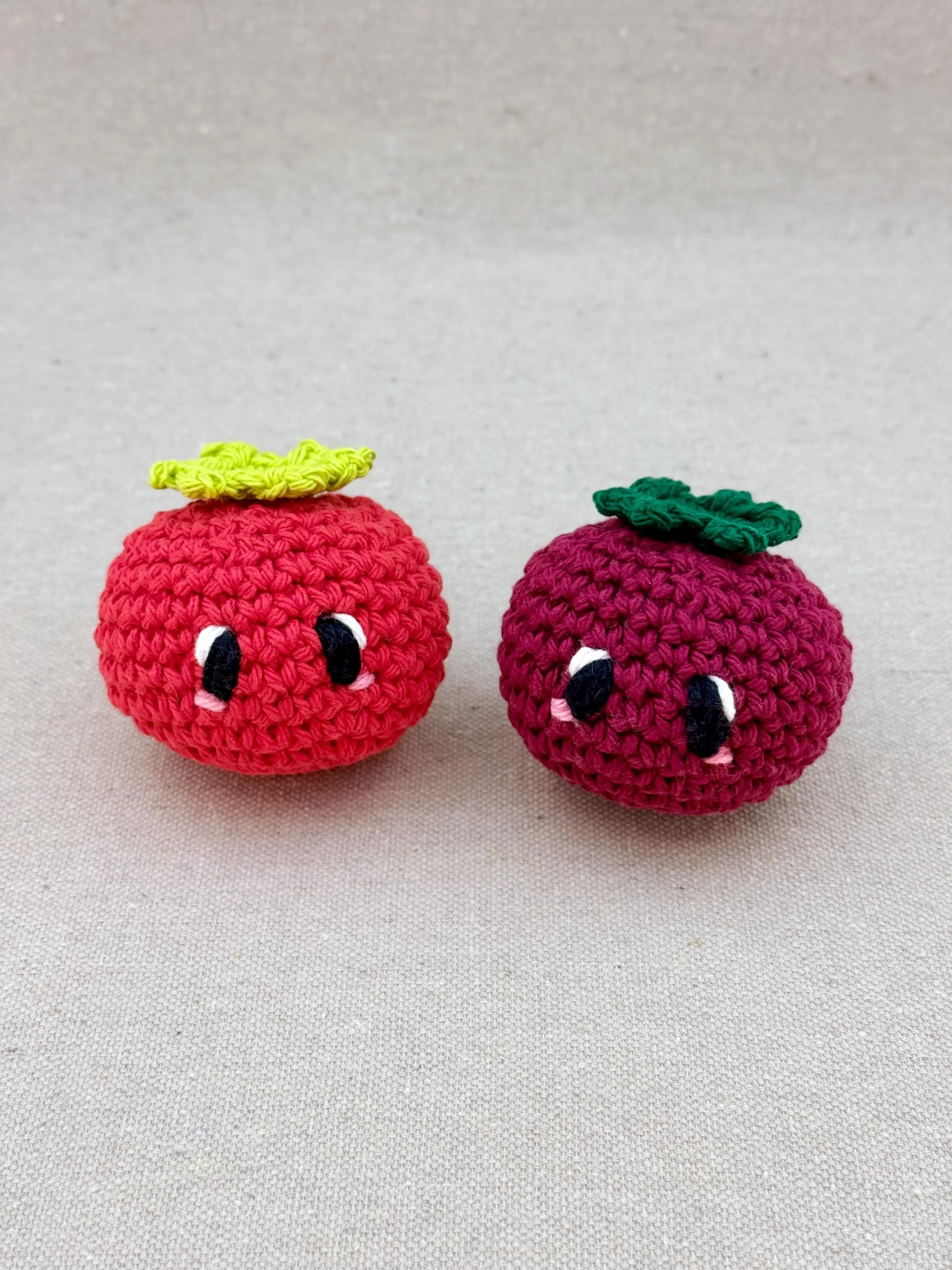 Two crochet tomatos in red and burgundy sitting next to each other (Copy)