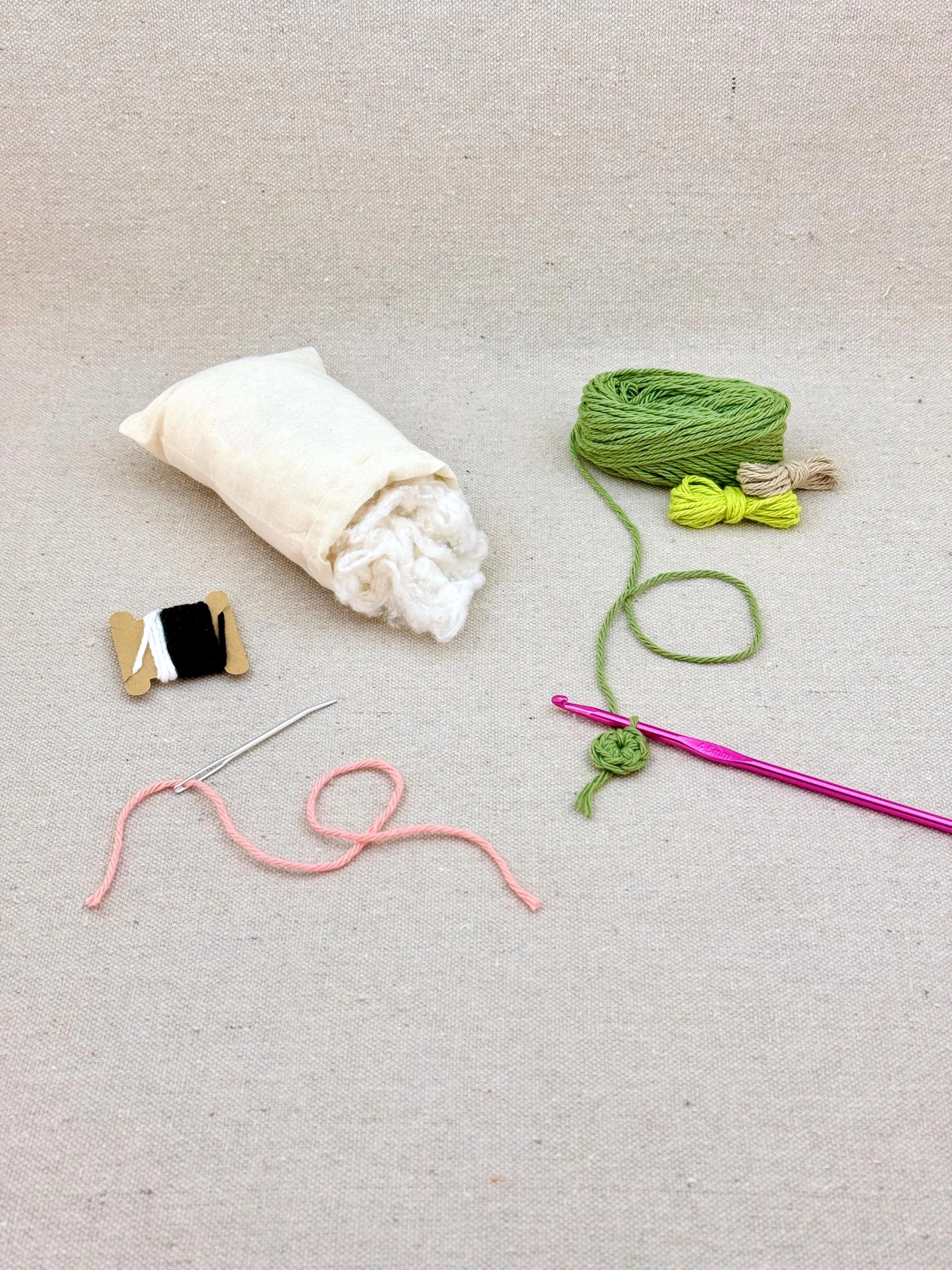 A sage green amigurumi pear mid project using a DIY crochet kit