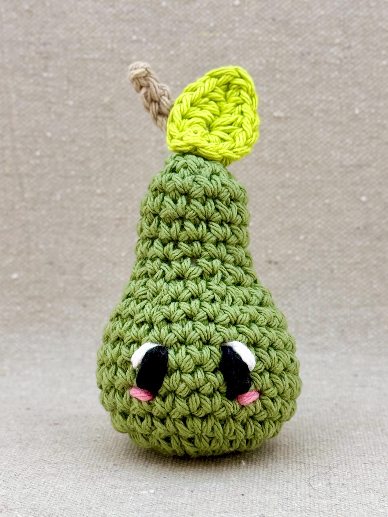 Close up of a sage green pear amigurumi plush made from cotton yarn and cotton stuffing (Copy)
