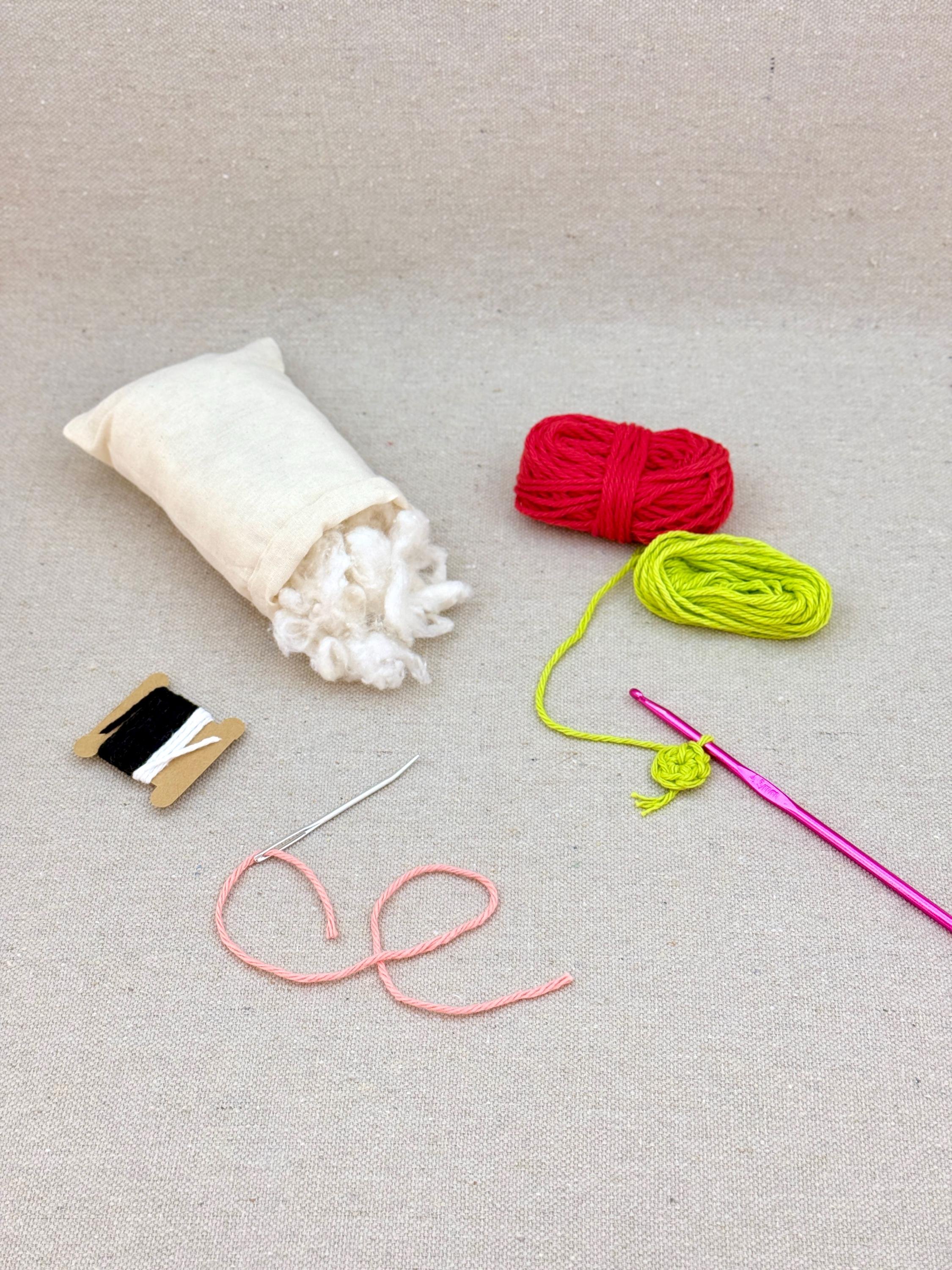 A red amigurumi strawberry mid project using a DIY crochet kit (Copy)