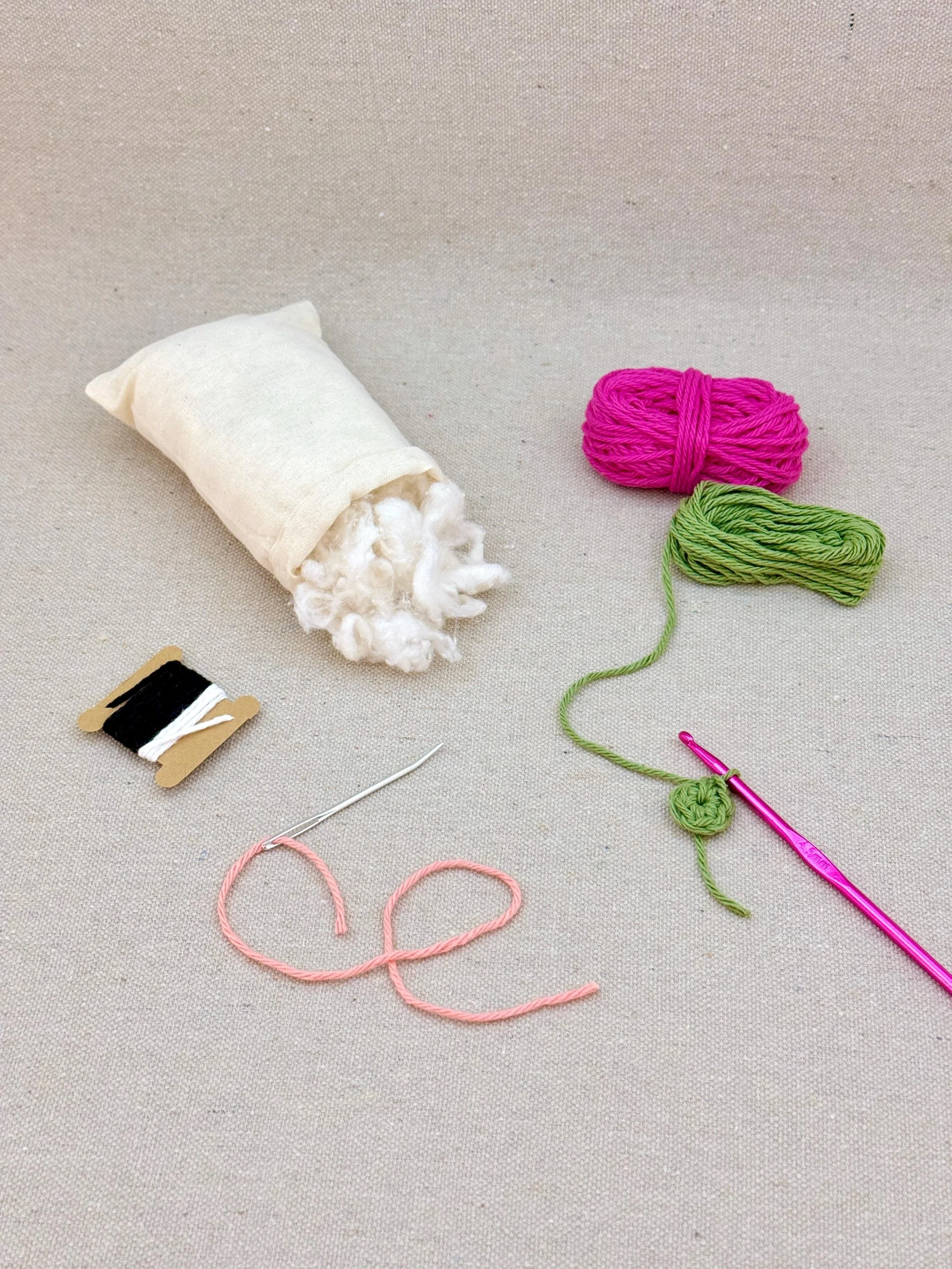 A hot pink amigurumi strawberry mid project using a DIY crochet kit