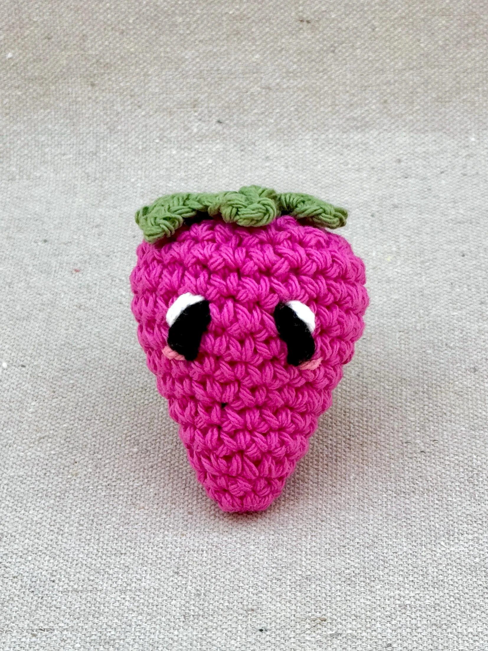 Close up of a hot pink strawberry amigurumi plush made from cotton yarn and cotton stuffing (Copy)